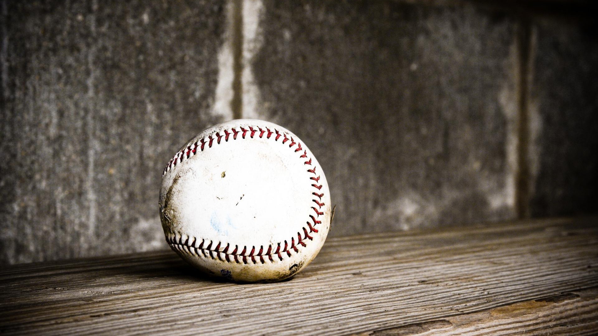 Baseball on wooden surface against concrete wall HD Wallpaper