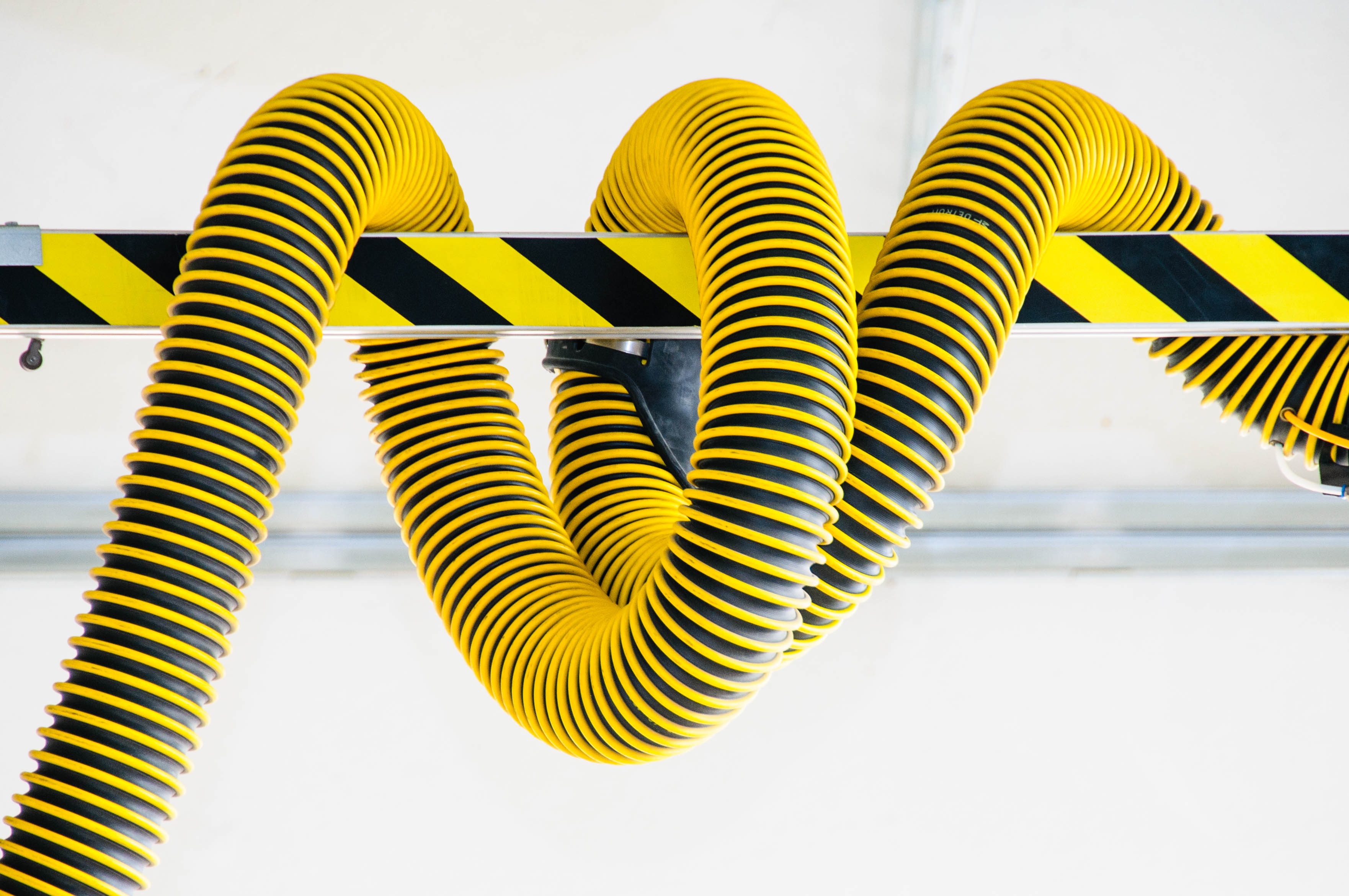 Yellow and black striped flexible hoses hanging from a beam HD Wallpaper