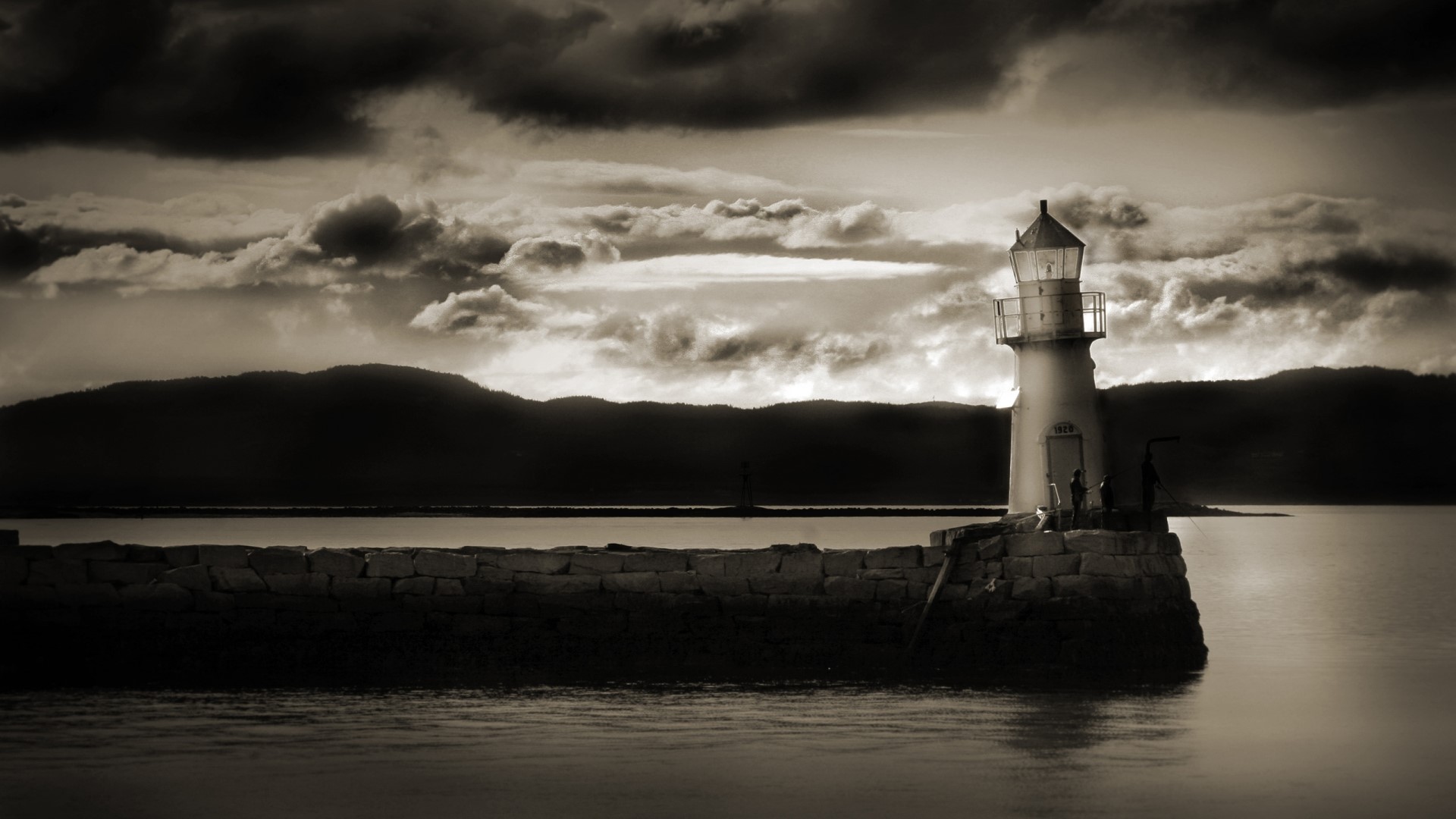Sepia lighthouse on a stone pier under a cloudy sky HD Wallpaper