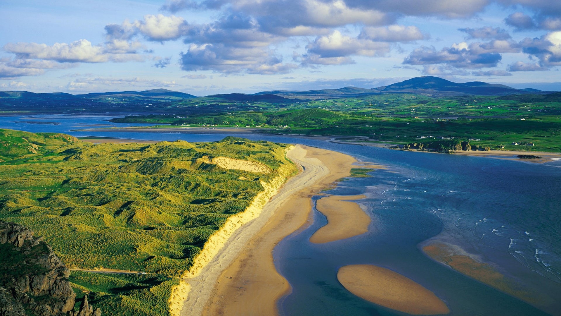 Aerial view of sand dunes and coastline with mountains HD Wallpaper