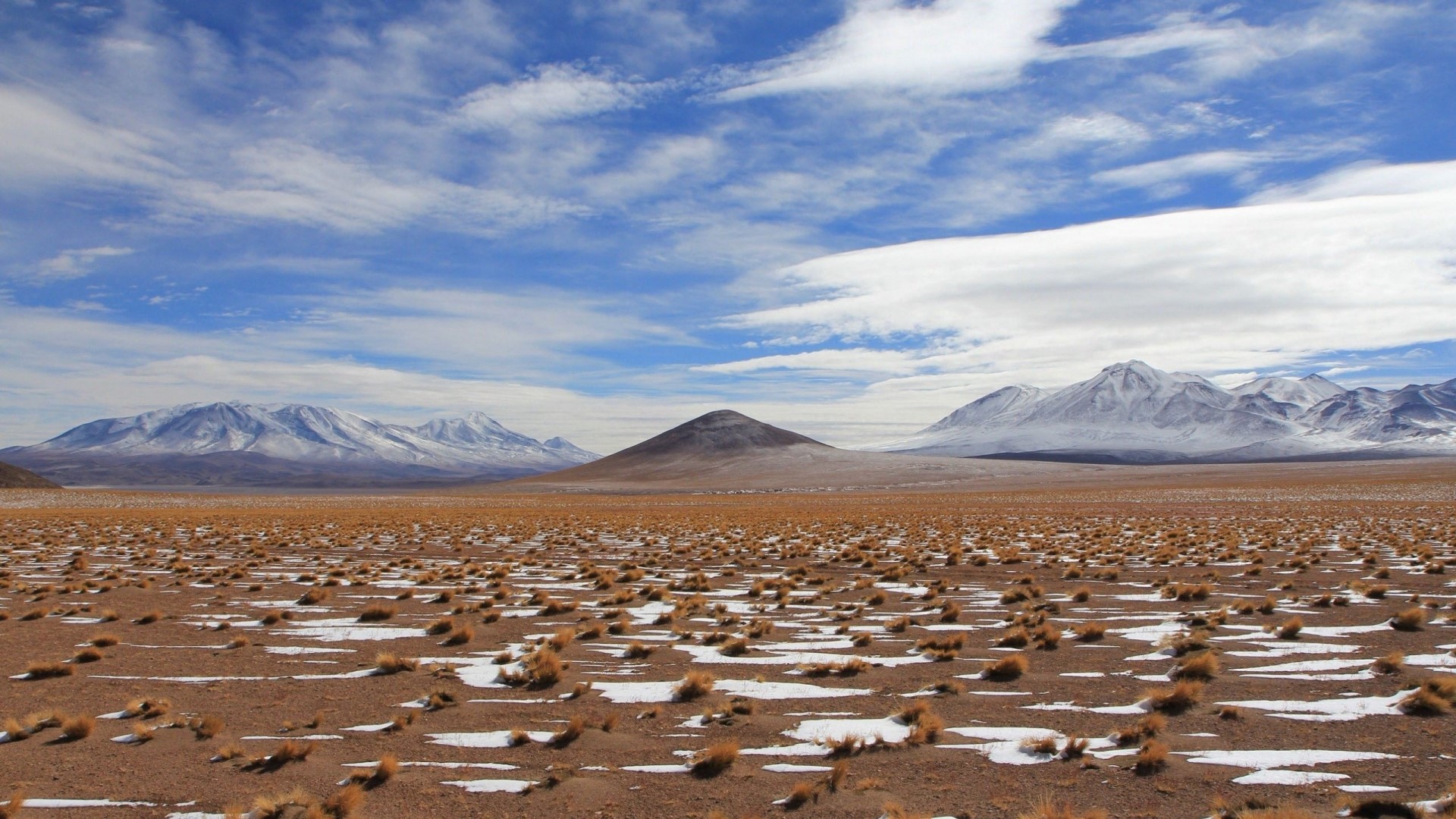 Snow-capped mountains in a dry, grassy landscape HD Wallpaper