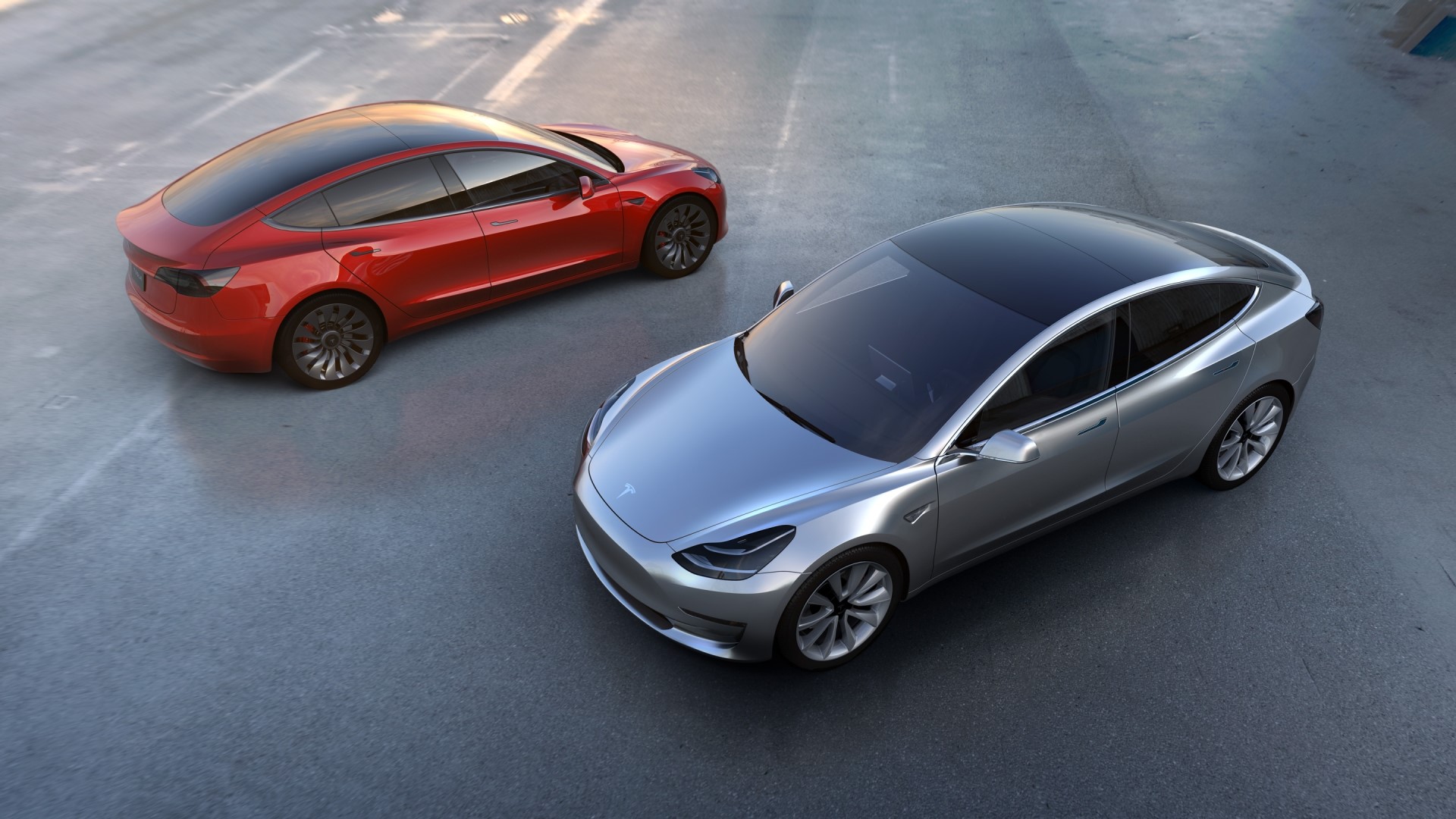 Two Tesla Model 3 cars on pavement HD Wallpaper