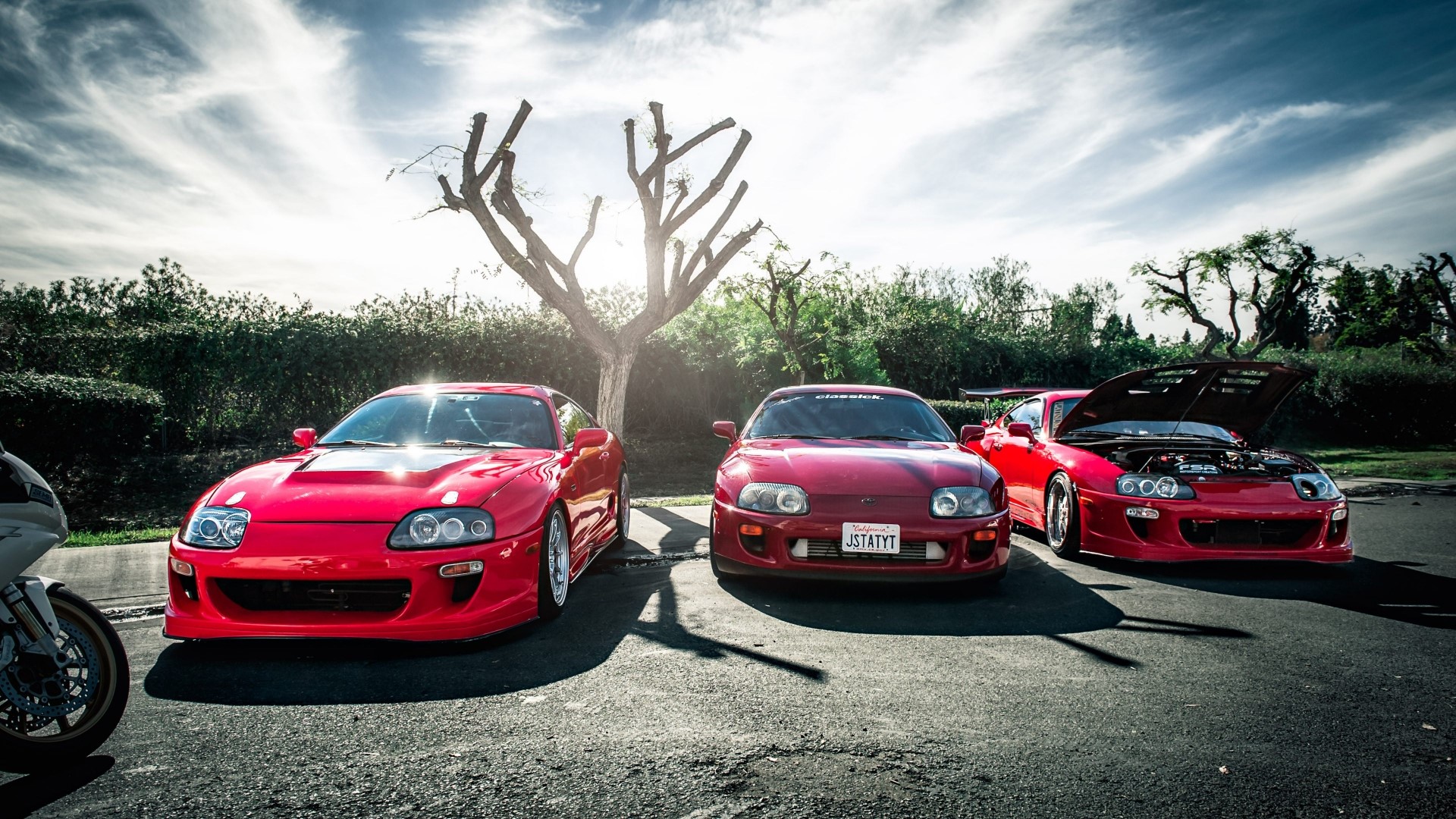 Three red Toyota Supra cars parked outdoors HD Wallpaper