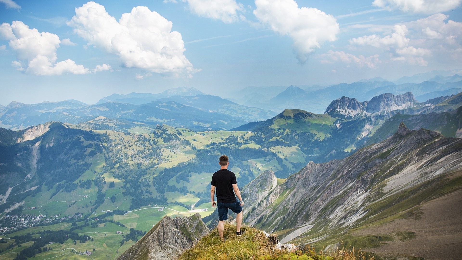 Man on mountain peak overlooking Alps HD Wallpaper