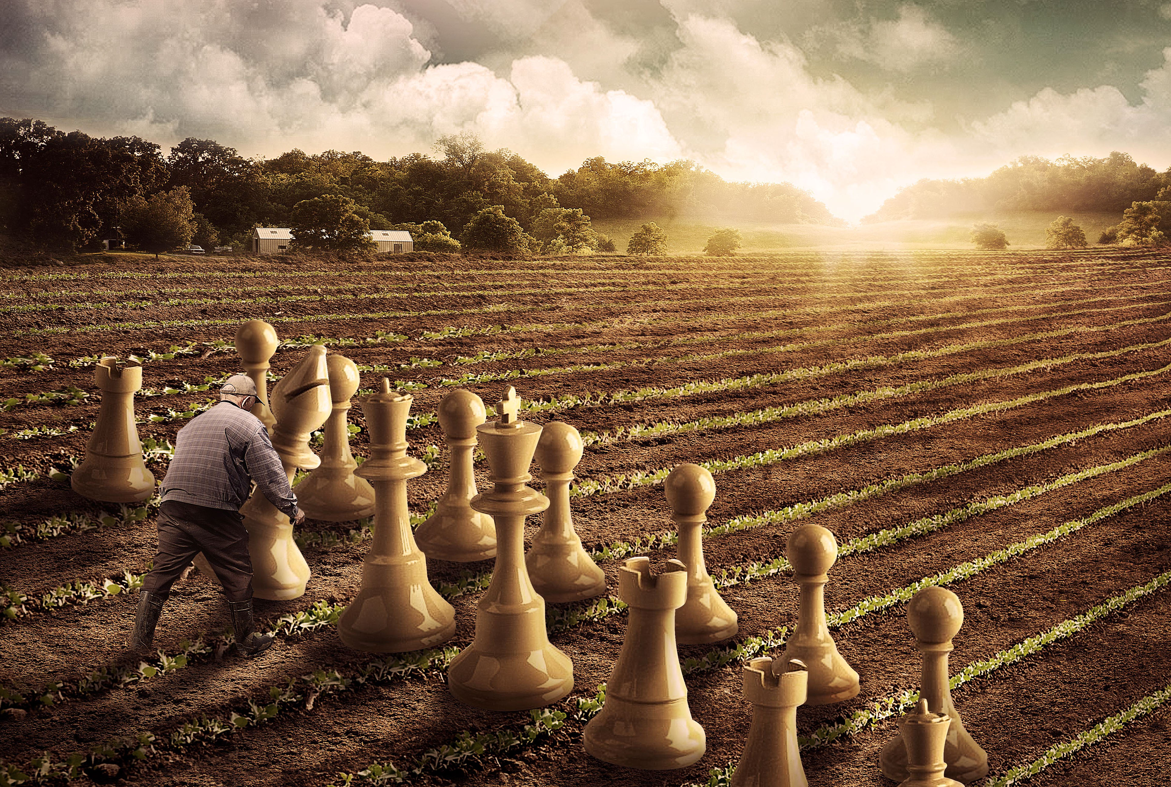 Man tending to giant chess pieces in a field HD Wallpaper