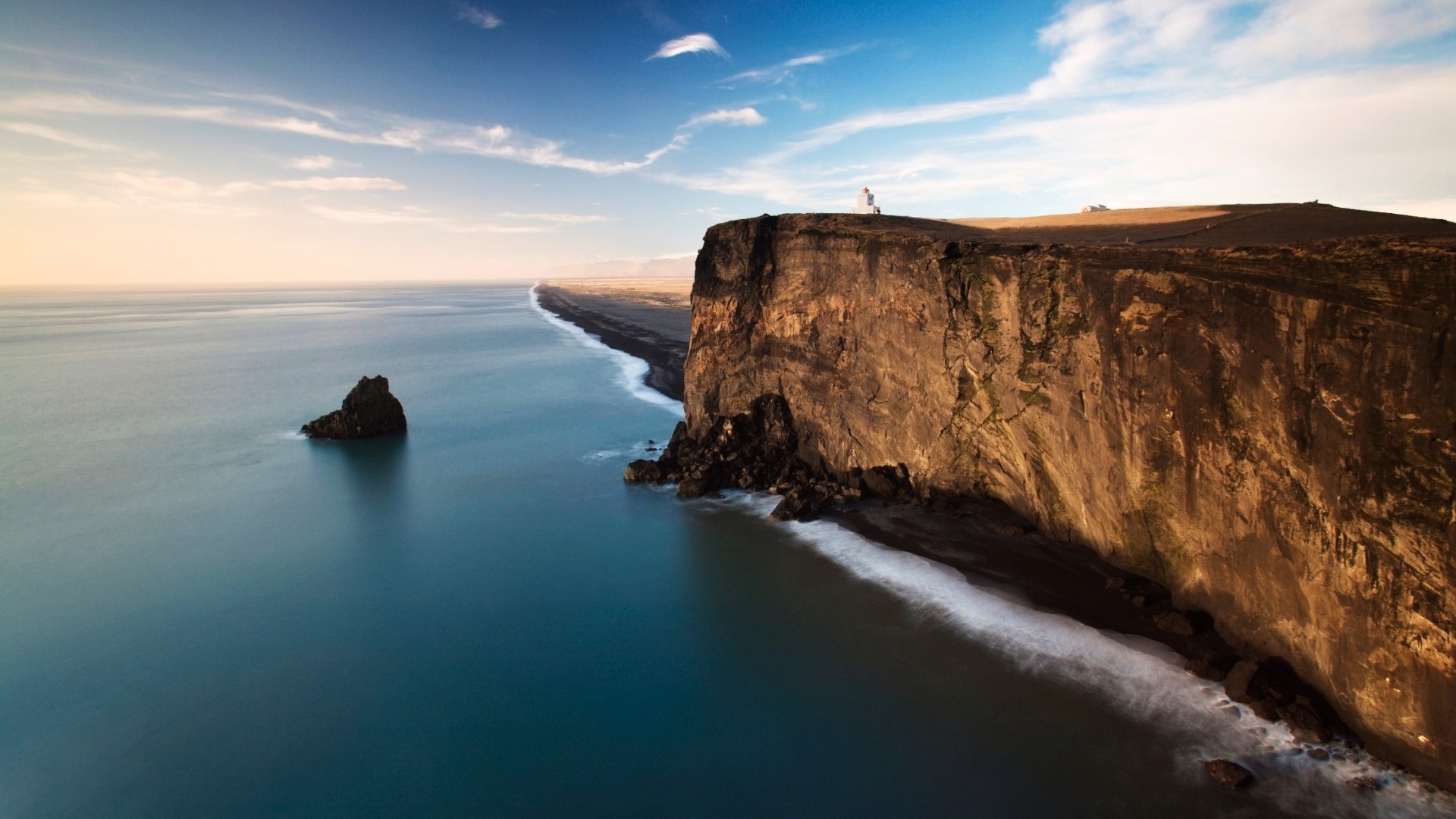 Person standing on a cliff overlooking the ocean HD Wallpaper
