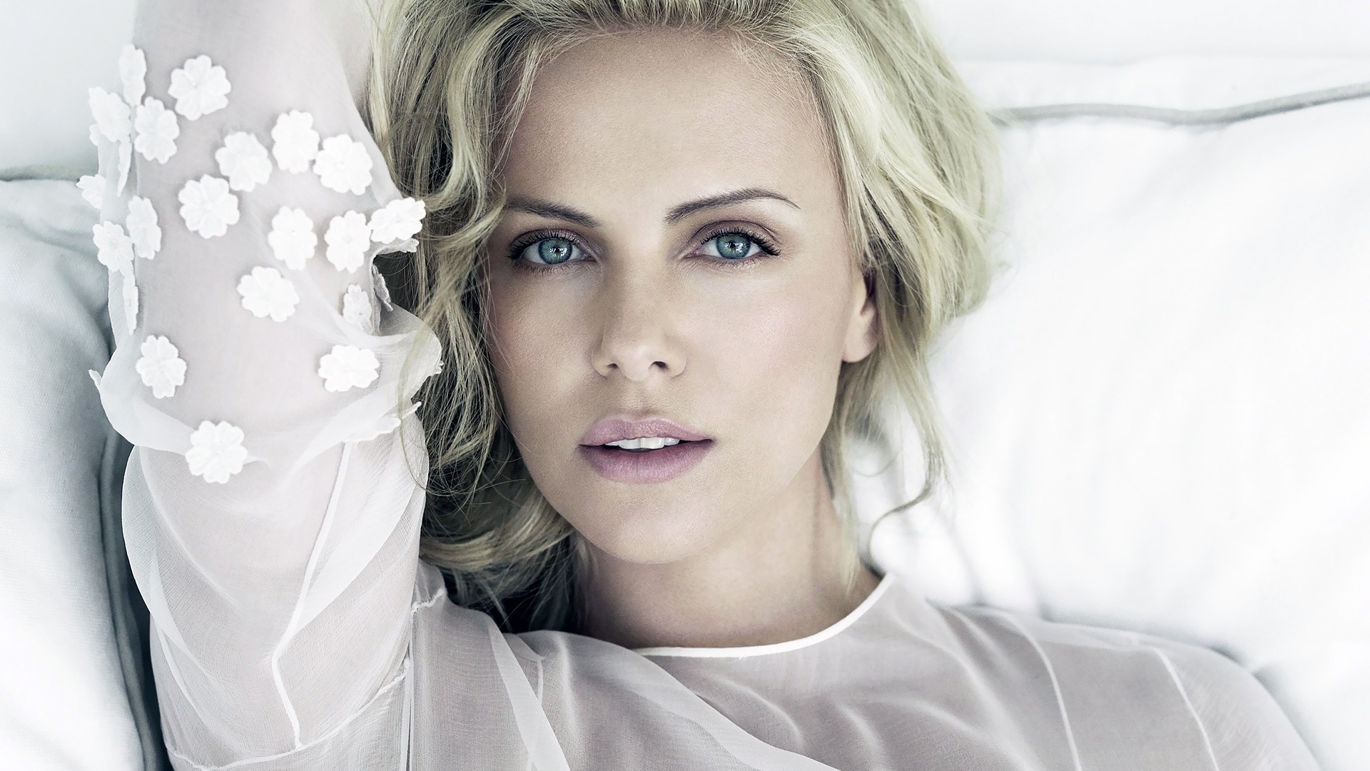 Charlize Theron lying on a white bed HD Wallpaper