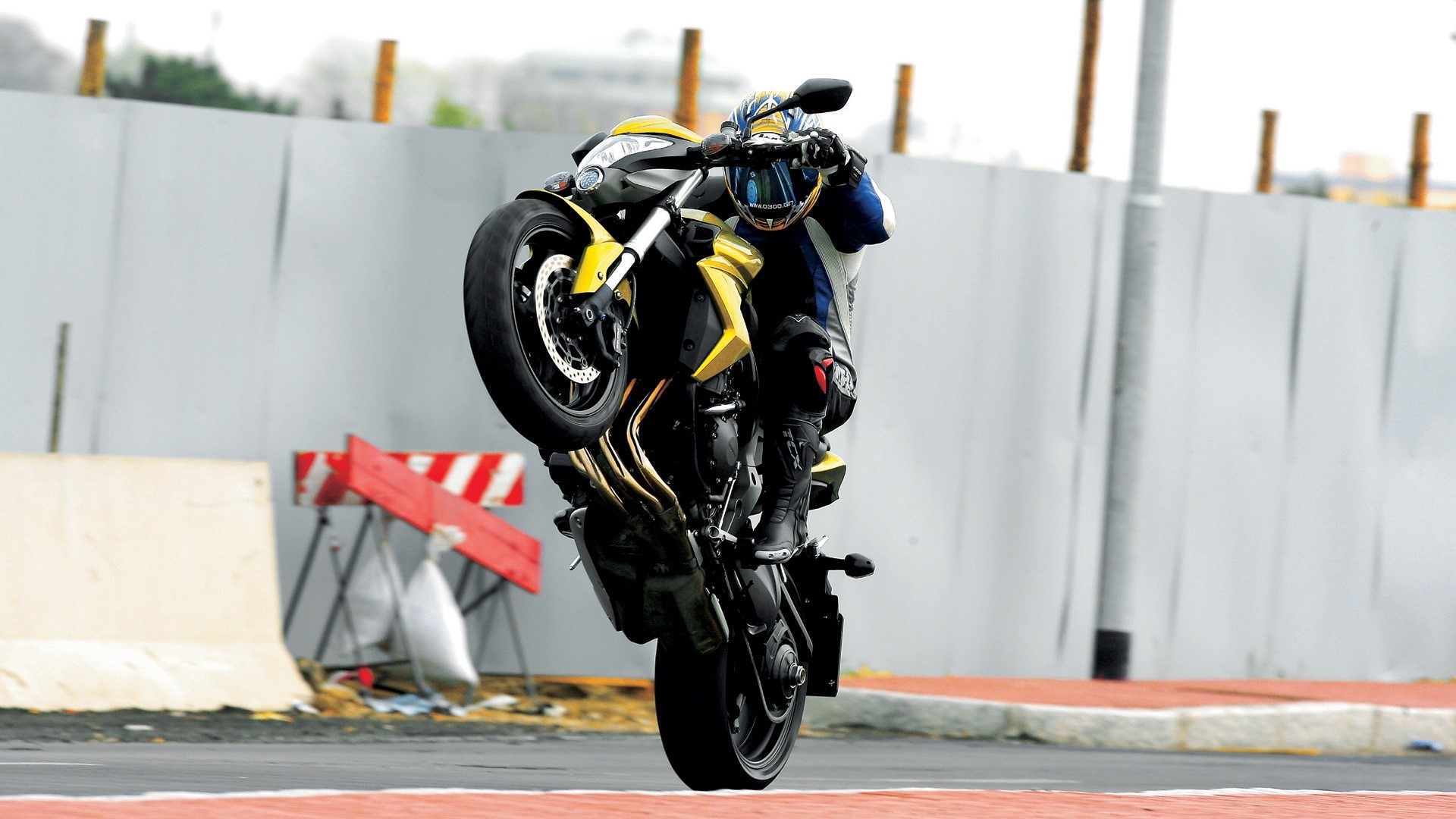 Motorcyclist performing a wheelie on a yellow Honda CB1000R HD Wallpaper