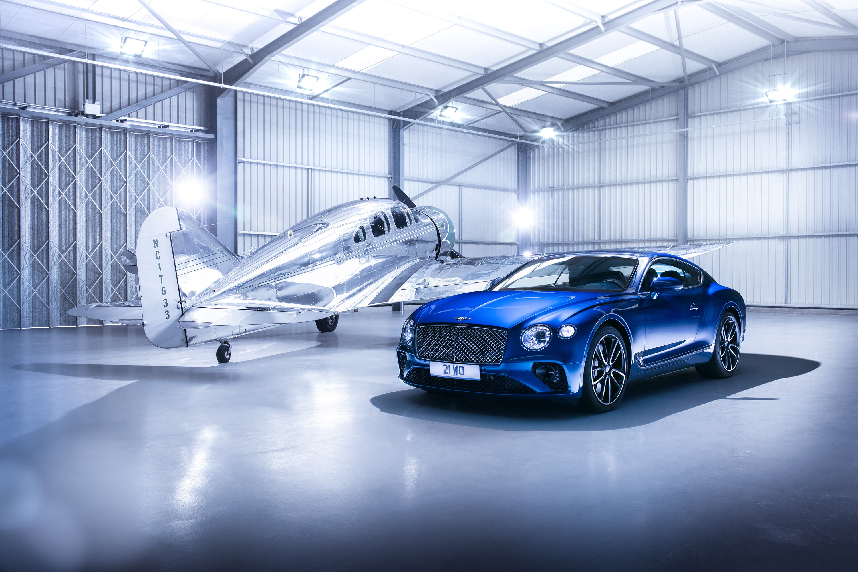 Bentley Continental GT and vintage airplane in hangar HD Wallpaper