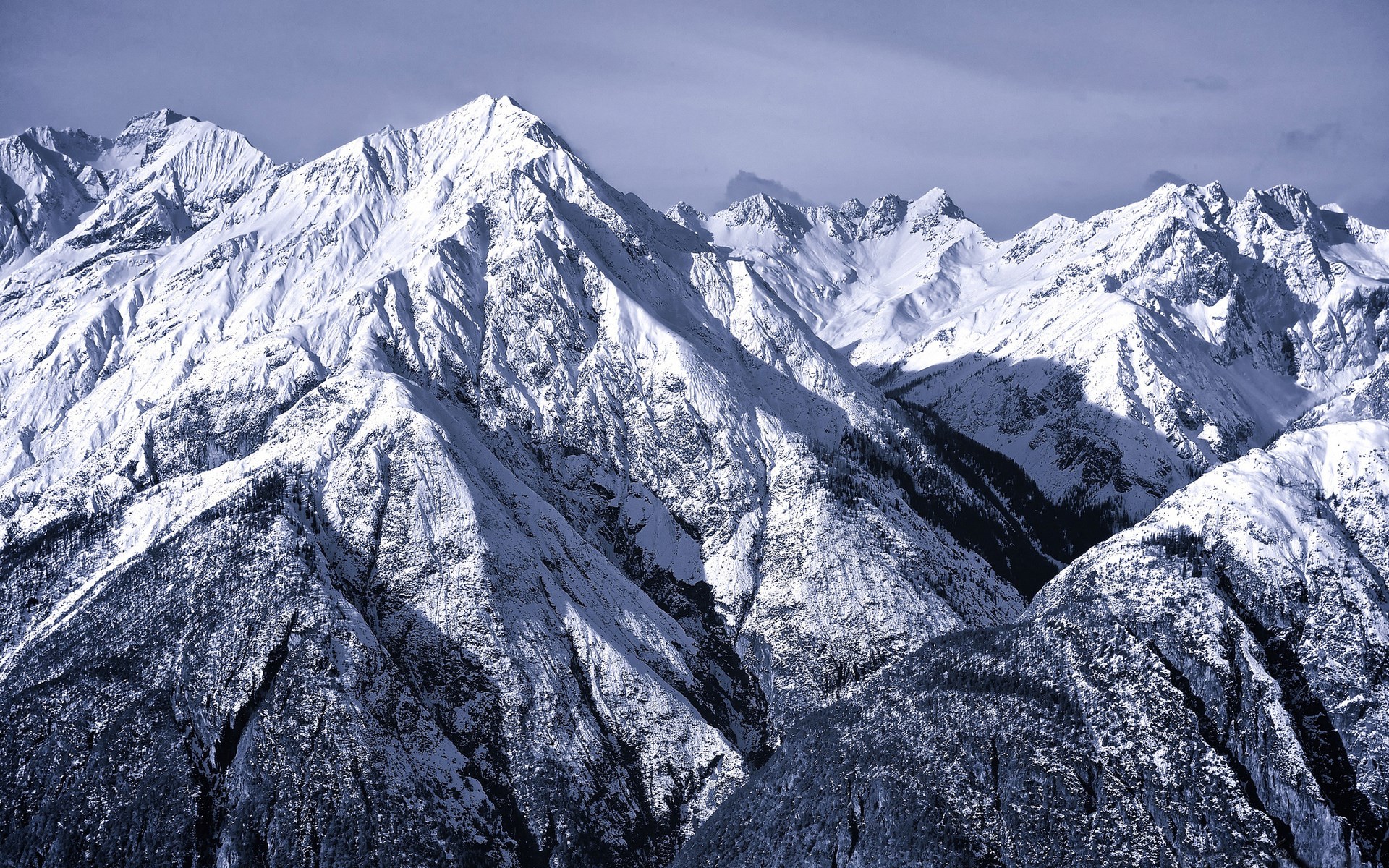 Snow-covered mountains under a cloudy sky HD Wallpaper