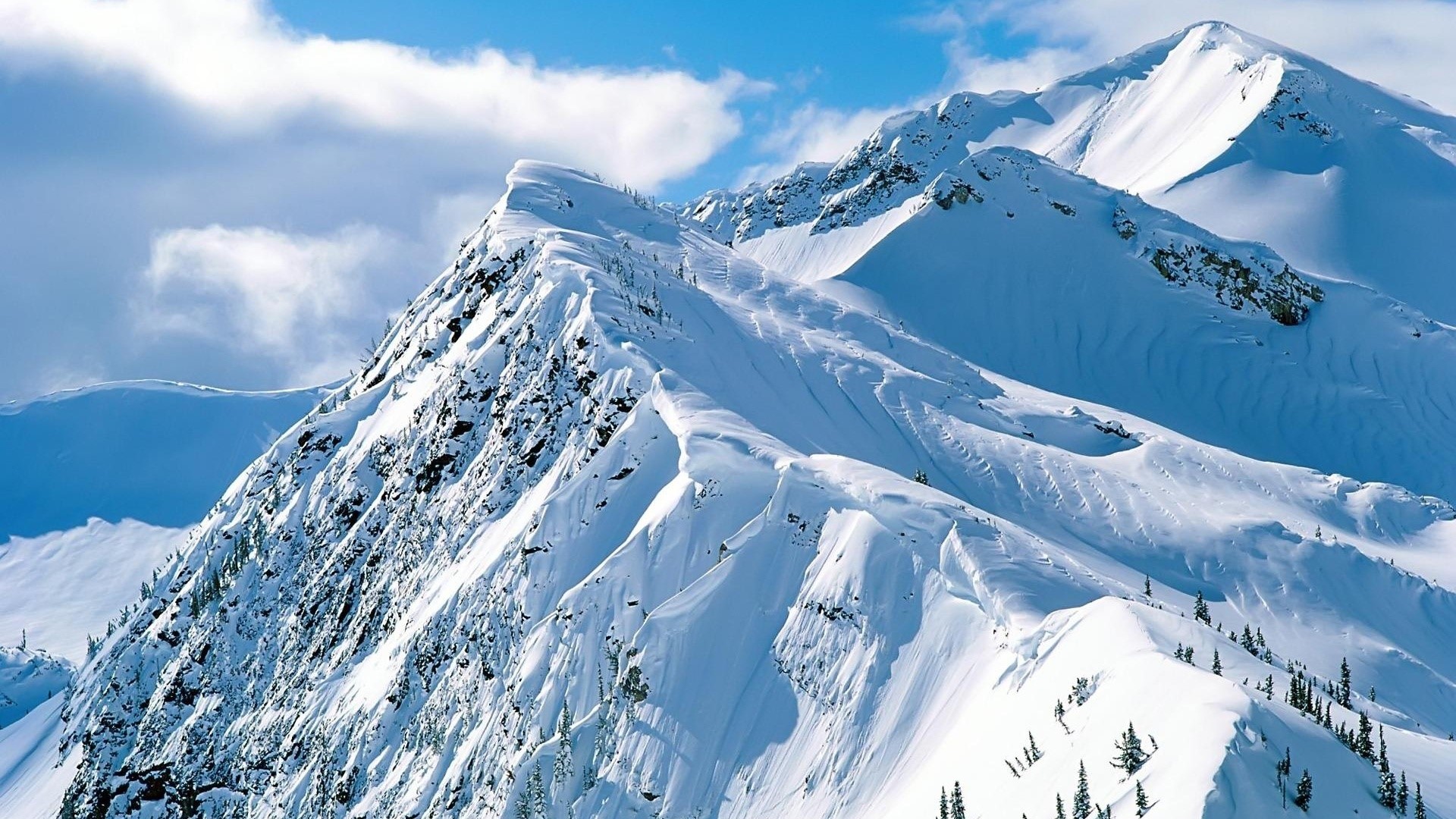 Snowy mountain range under a blue sky HD Wallpaper