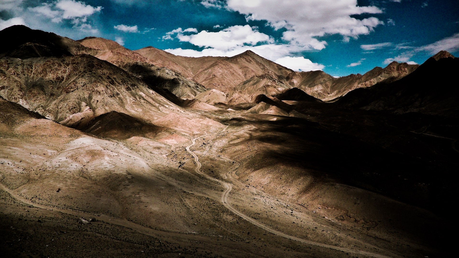 Mountain valley with winding road and clouds HD Wallpaper