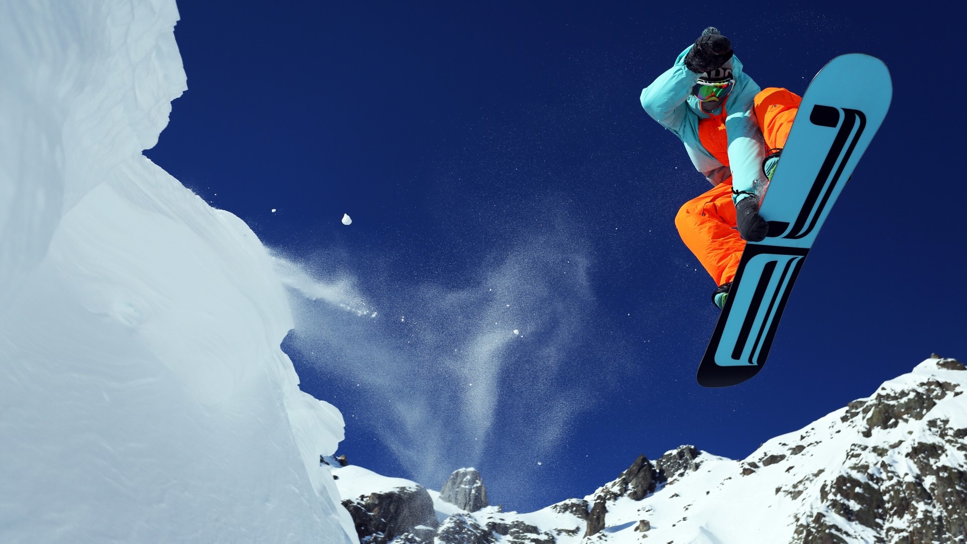 Snowboarder jumping off a snowy cliff HD Wallpaper