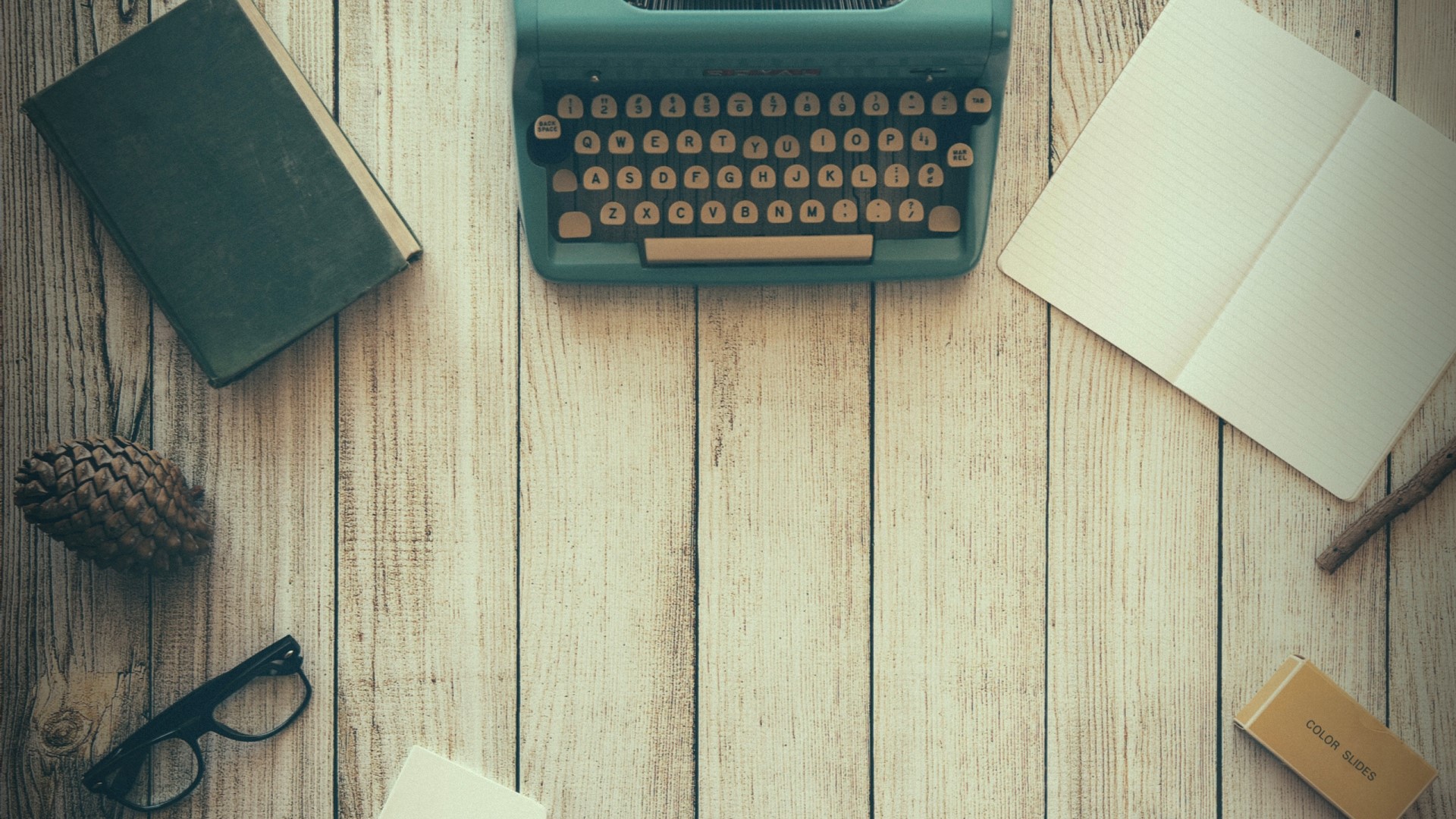 Typewriter, book, notebook, and glasses on a wooden desk HD Wallpaper