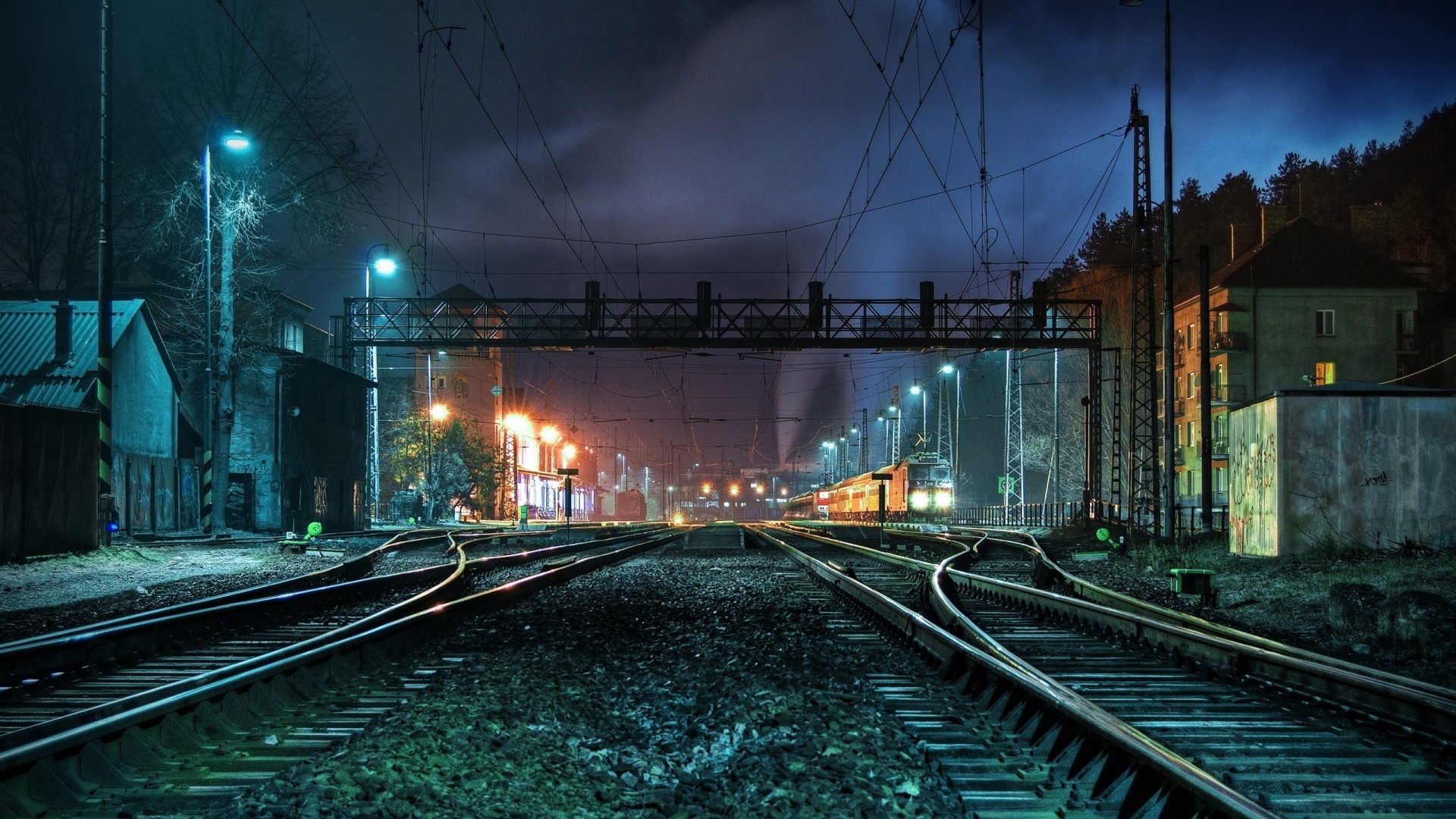 Train tracks at a station at night HD Wallpaper