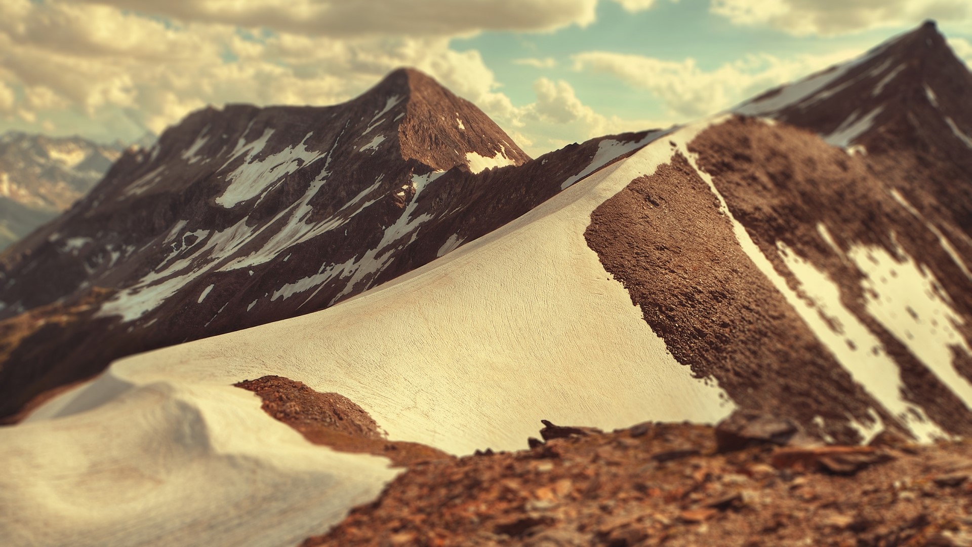 Snow-covered mountain peaks under a cloudy sky HD Wallpaper