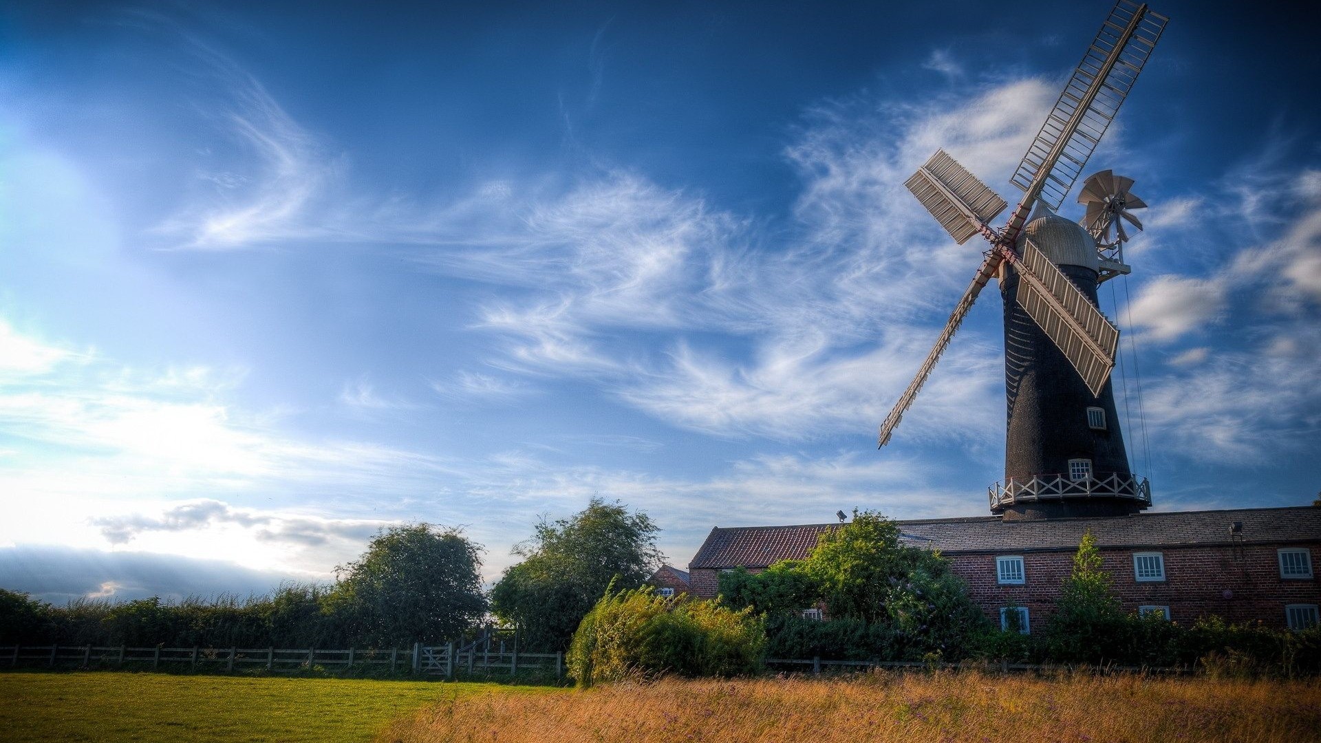 Windmill with brick building and grassy field HD Wallpaper