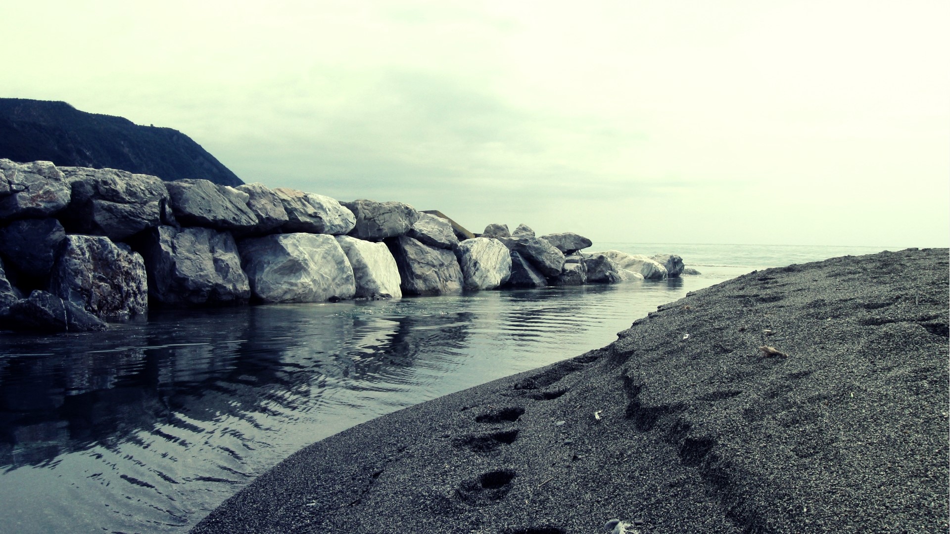 Rocky breakwater and black sand beach HD Wallpaper