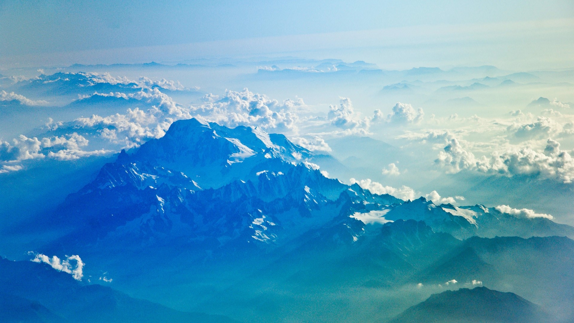Snow-capped mountains above clouds from airplane HD Wallpaper