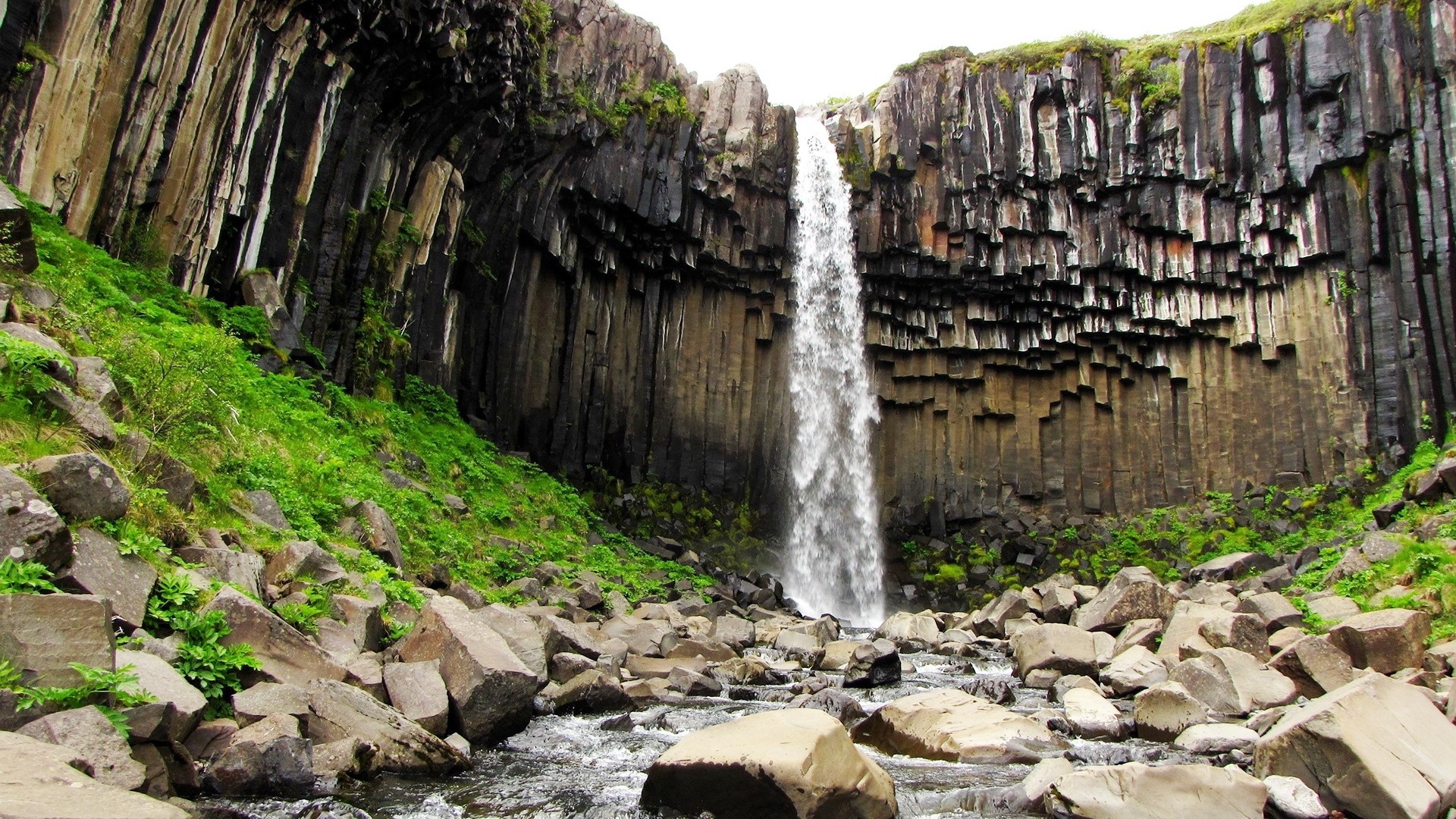 Waterfall cascading over basalt columns HD Wallpaper