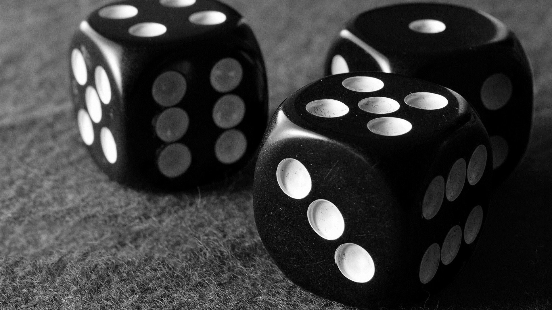 Three black dice on a textured surface HD Wallpaper