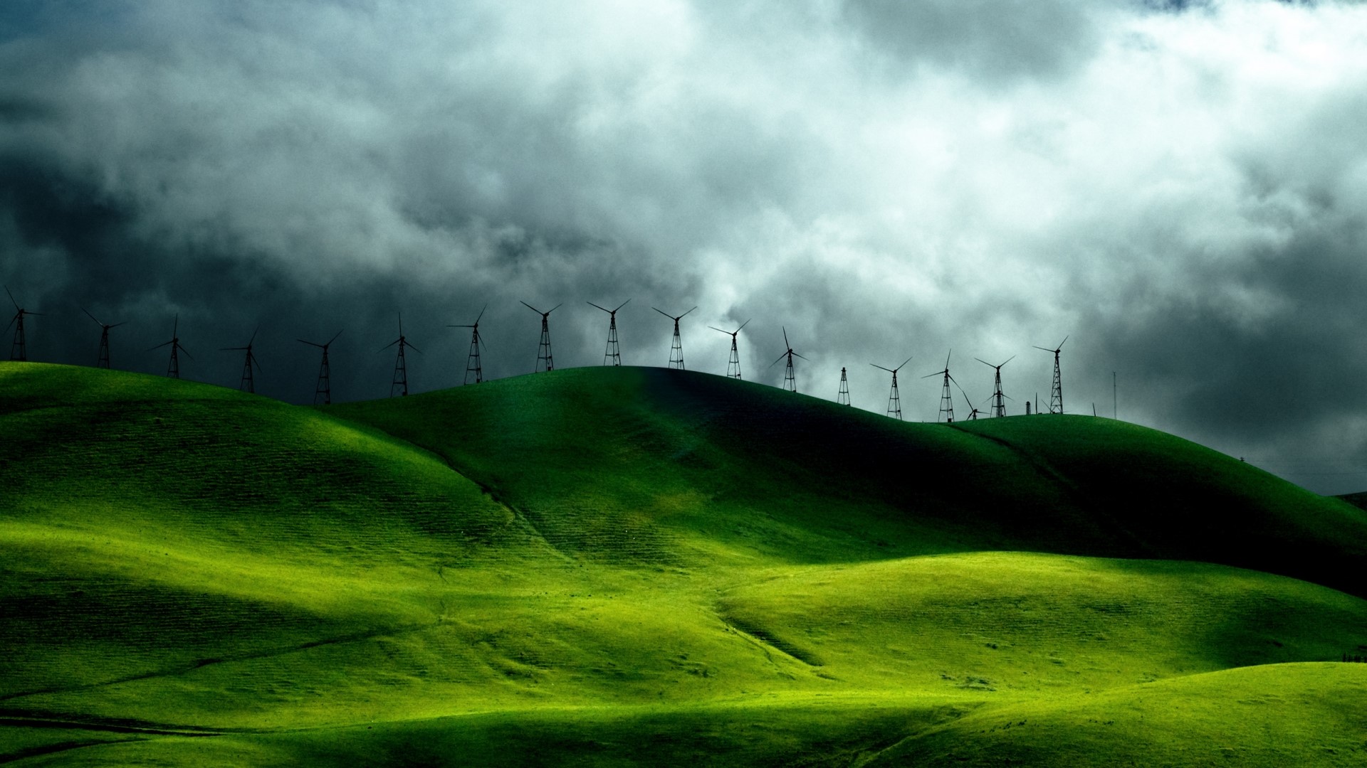 Wind turbines on green hills under stormy clouds HD Wallpaper