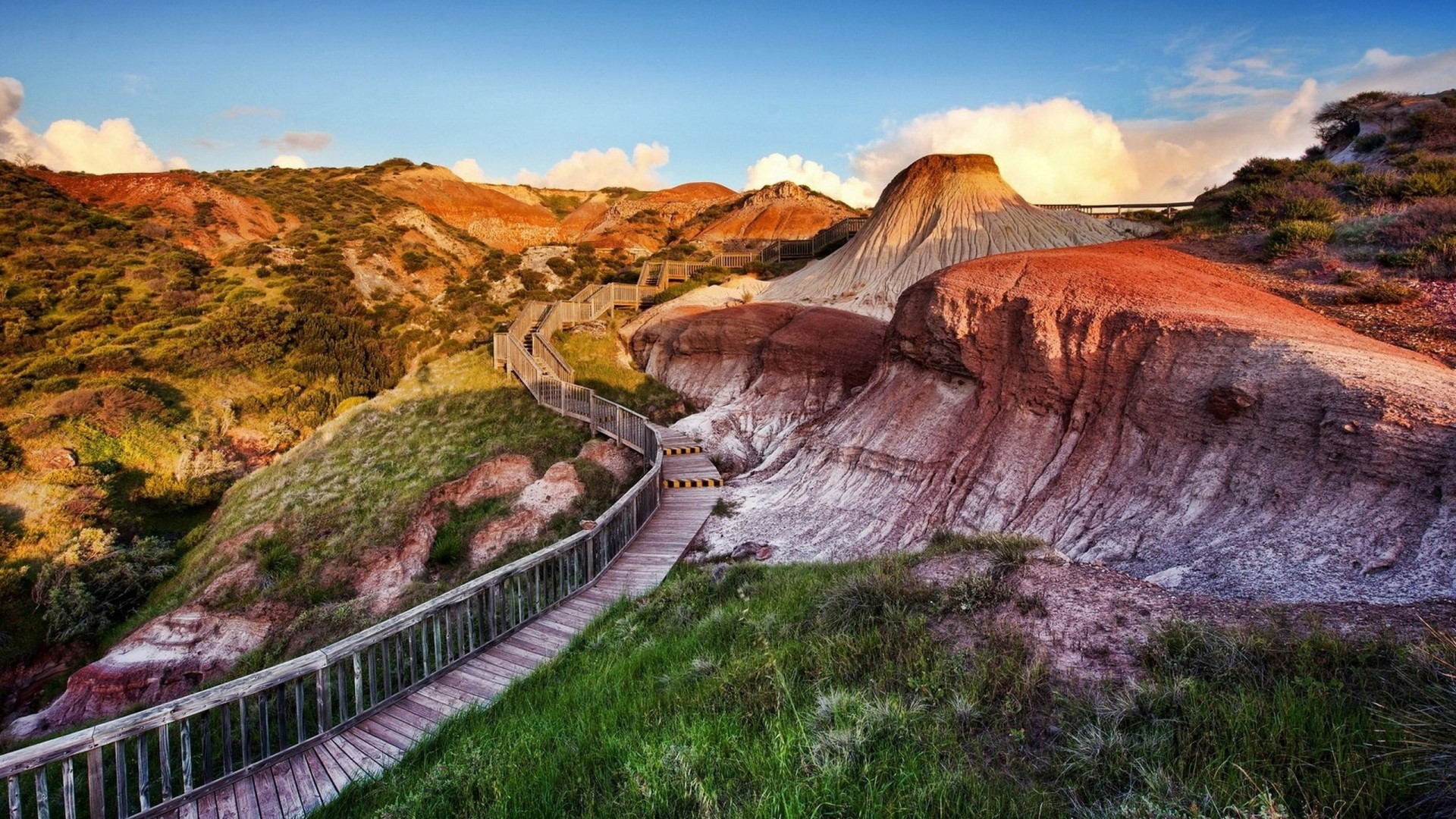 Wooden boardwalk through colorful badlands landscape HD Wallpaper