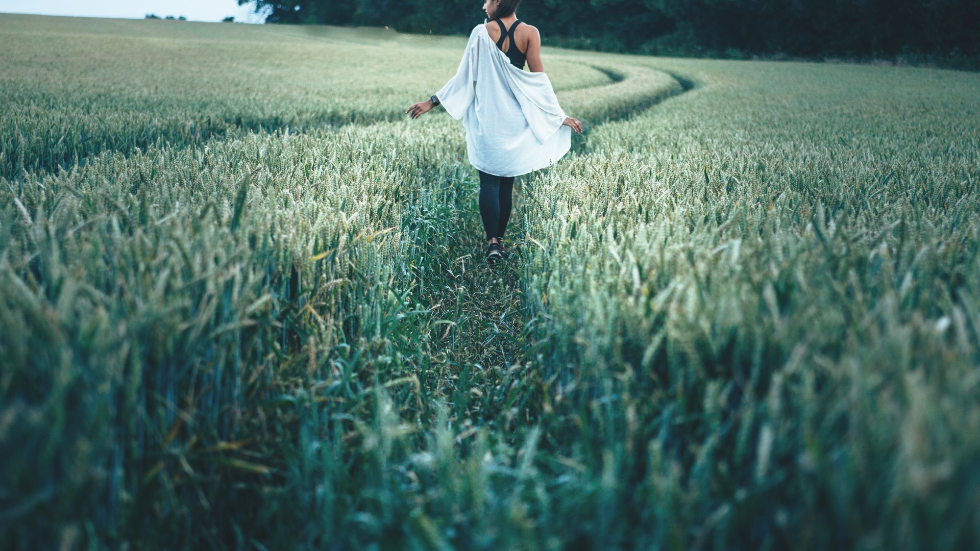 Woman walking through a wheat field HD Wallpaper