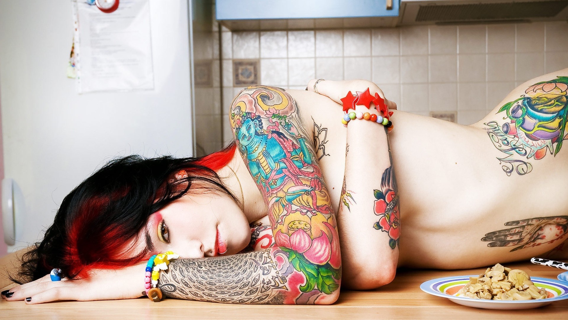 Tattooed woman lying on a kitchen counter HD Wallpaper