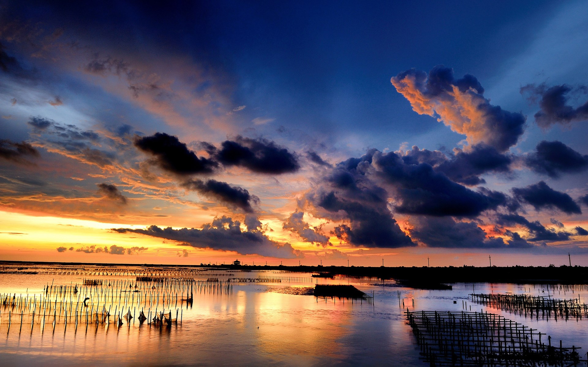 Sunset over a body of water with wooden structures HD Wallpaper