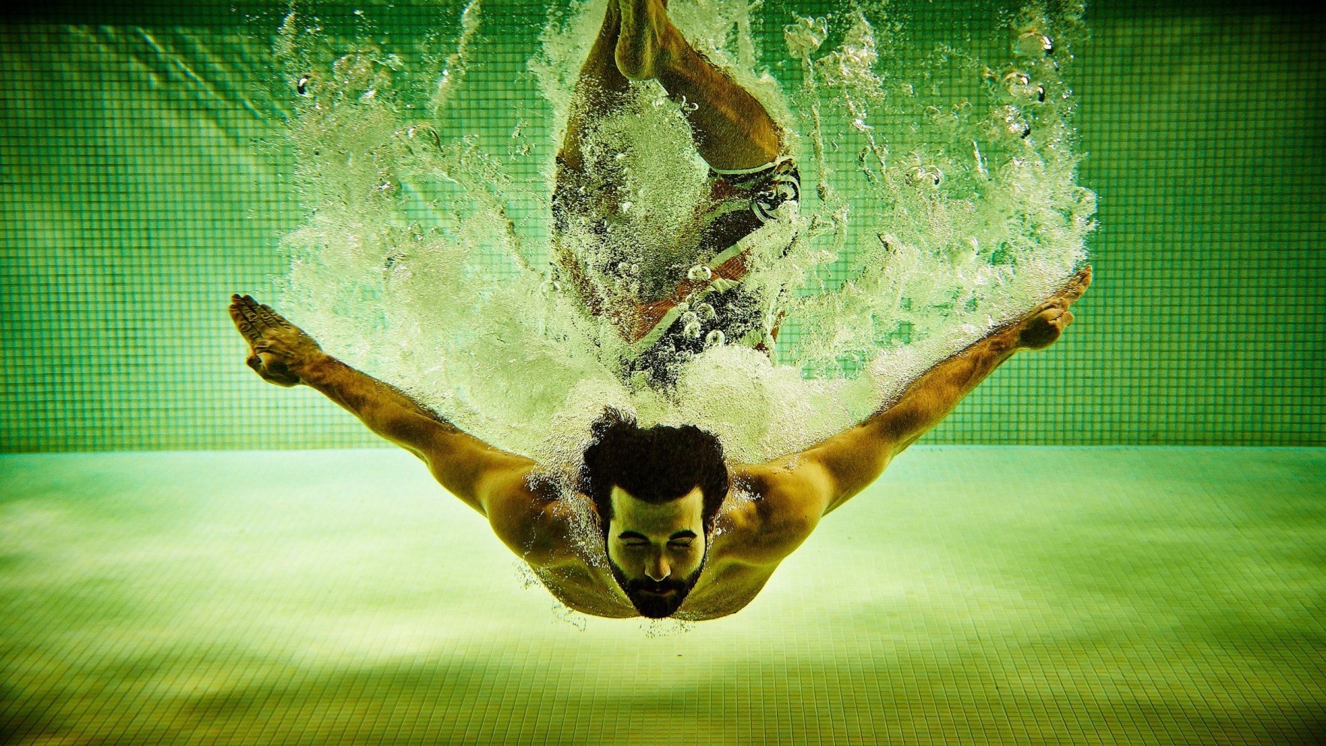 Man diving underwater in a swimming pool HD Wallpaper