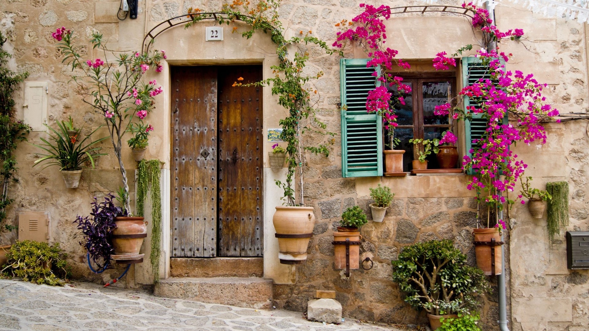 Stone house with wooden door and flowers in Majorca, Spain HD Wallpaper