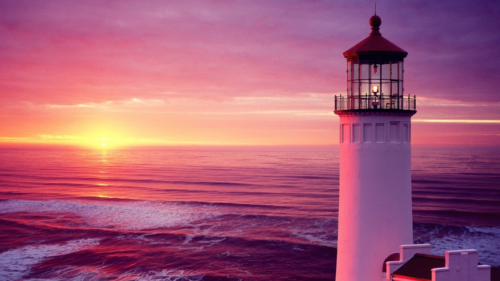 Lighthouse at sunset over the ocean HD Wallpaper