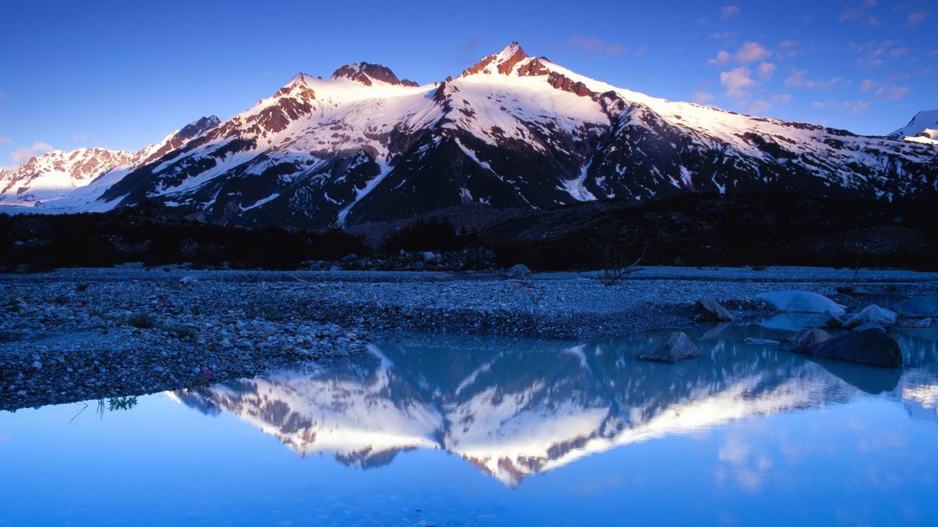 Snow-capped mountains reflected in a calm lake HD Wallpaper