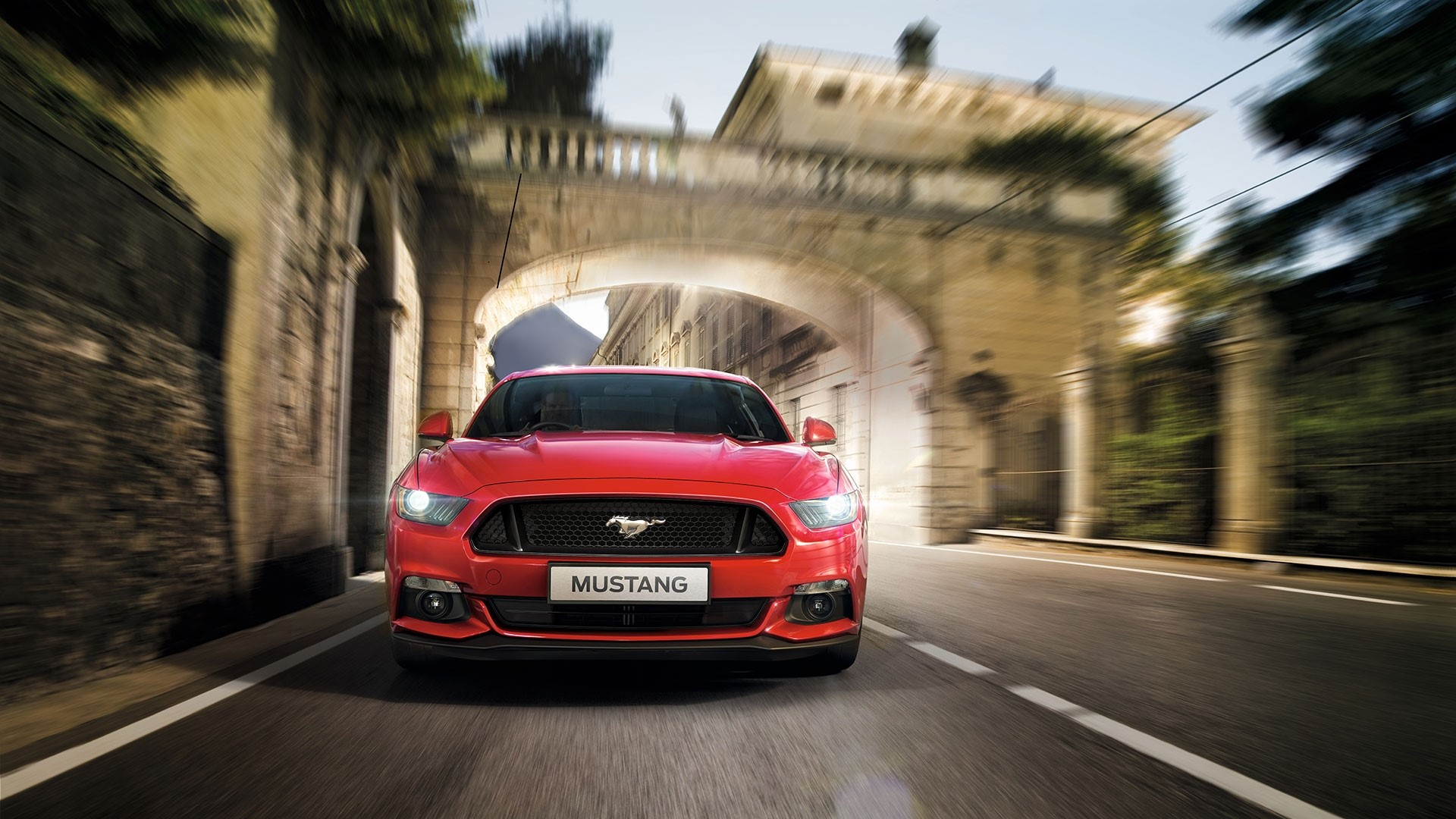 Red Ford Mustang driving through an archway HD Wallpaper