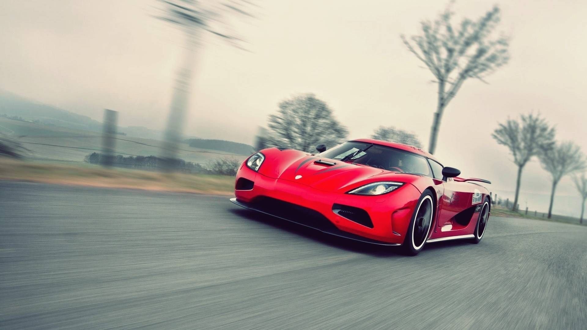Red Koenigsegg Agera driving on a road HD Wallpaper