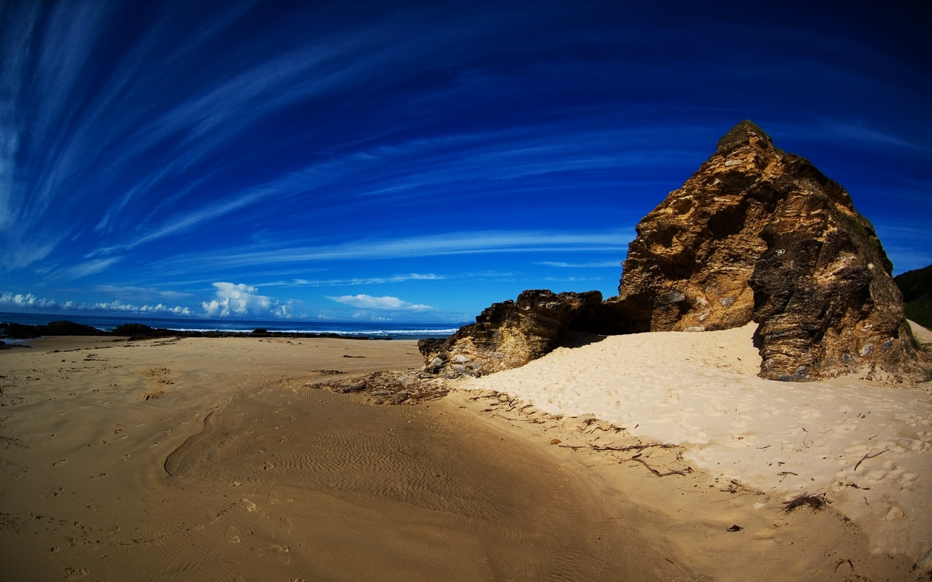 Beach with rock formation and wispy clouds HD Wallpaper