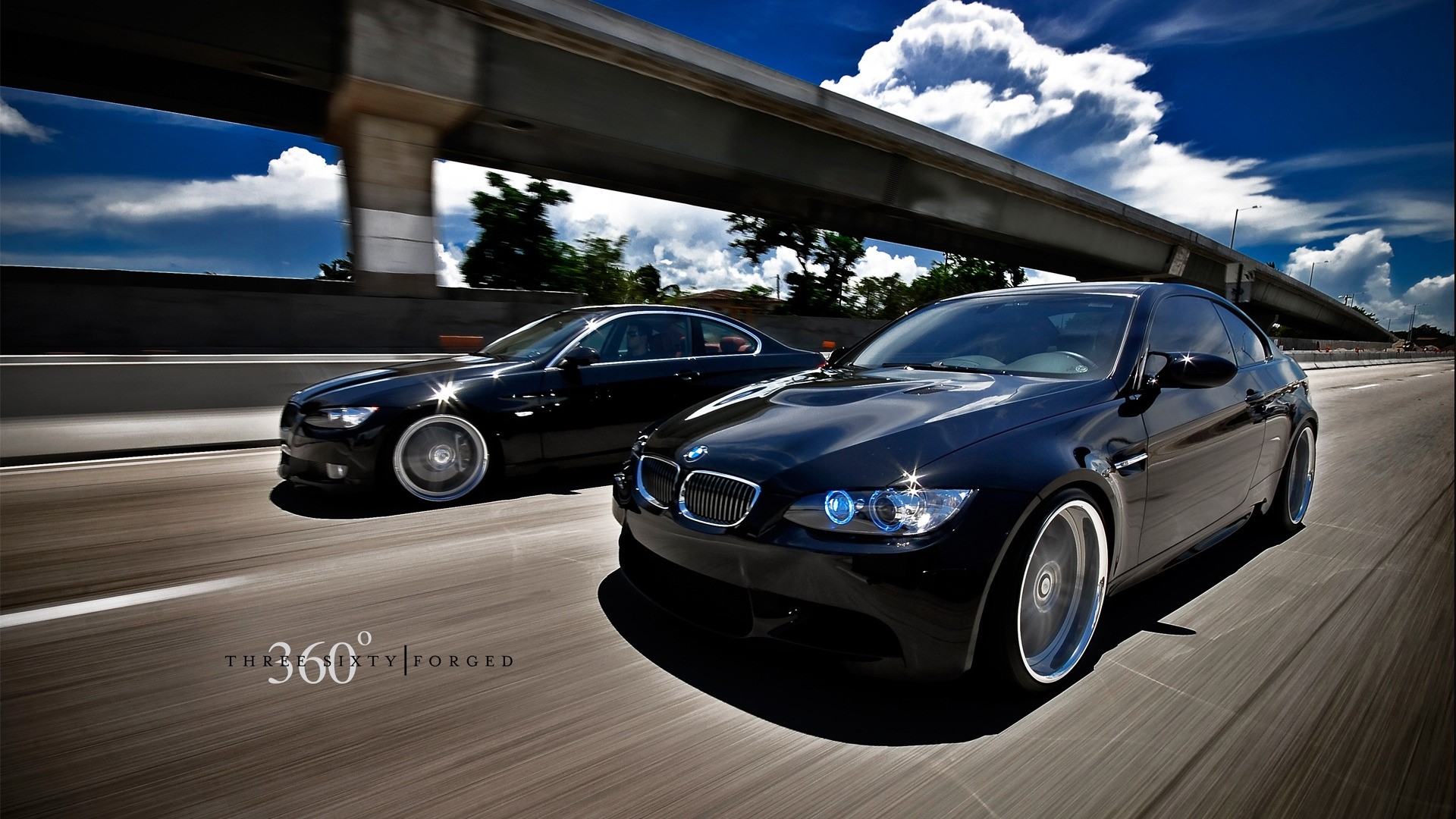 Two black BMWs driving on a highway HD Wallpaper
