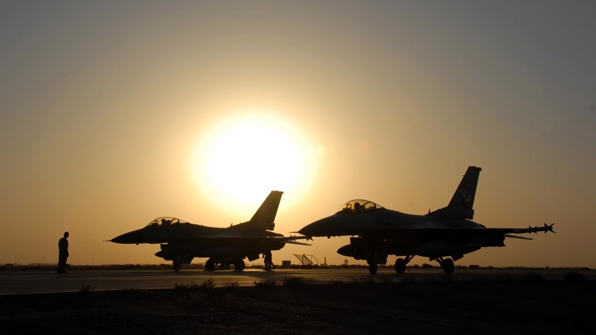 Two F-16 fighter jets on tarmac at sunset HD Wallpaper