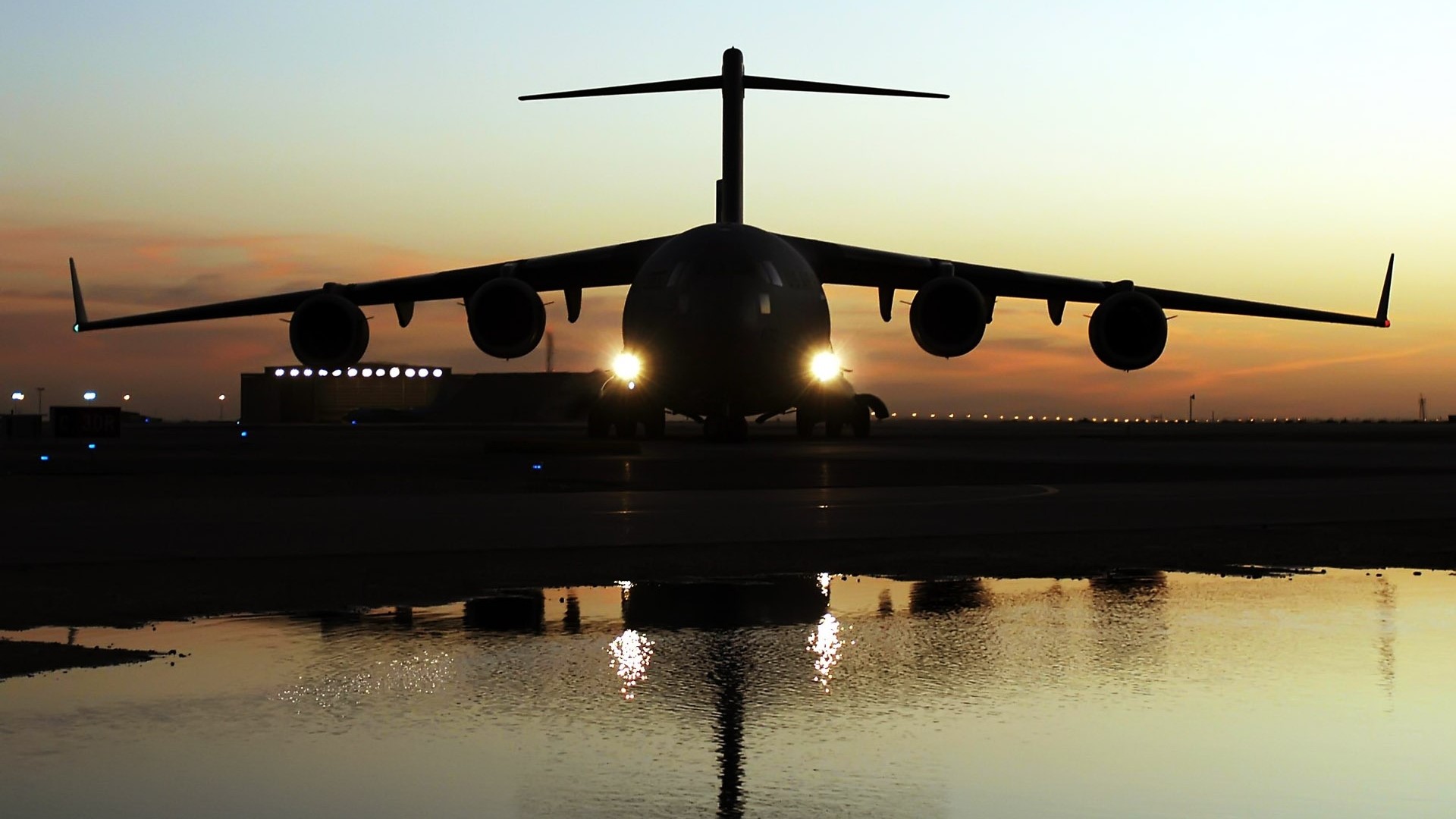 Silhouette of a large cargo airplane on a runway at sunset HD Wallpaper