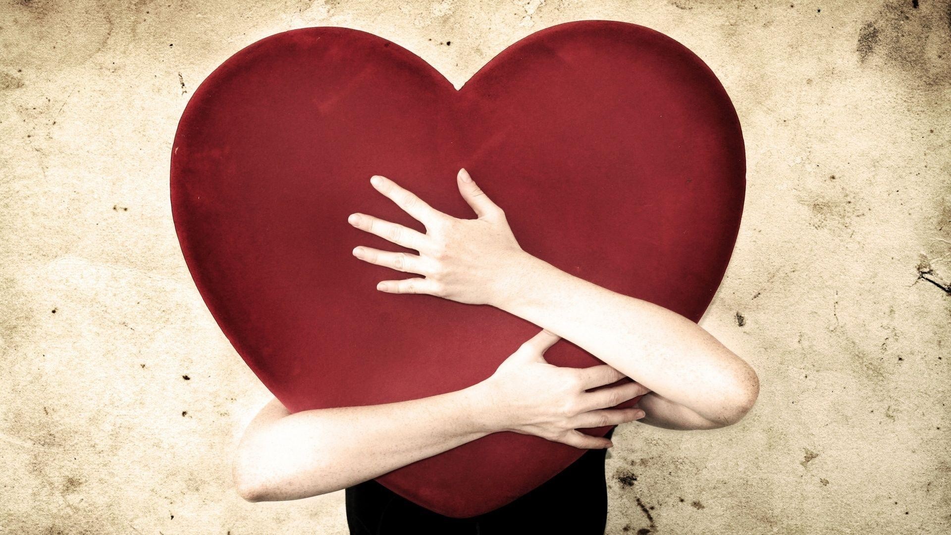 Person hugging a large red heart HD Wallpaper