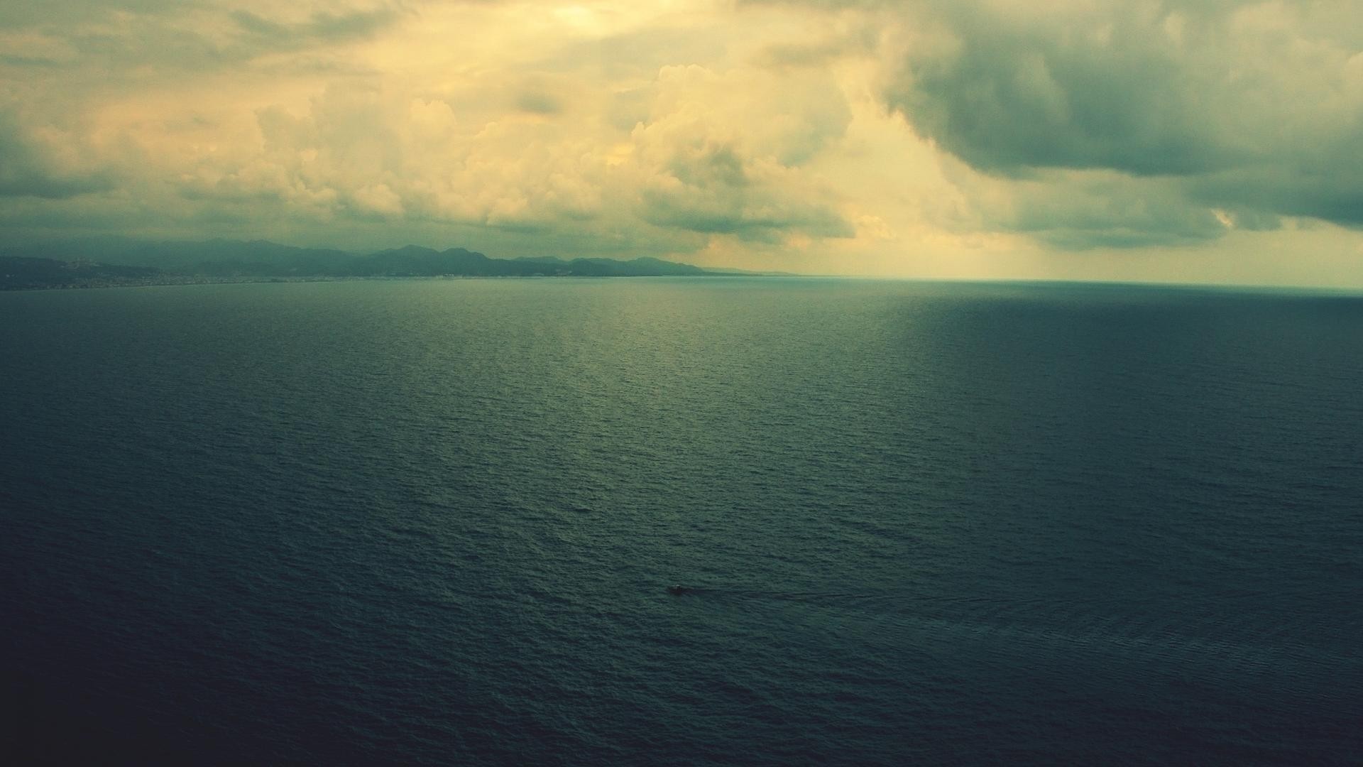 Ocean bay with storm clouds and a boat HD Wallpaper