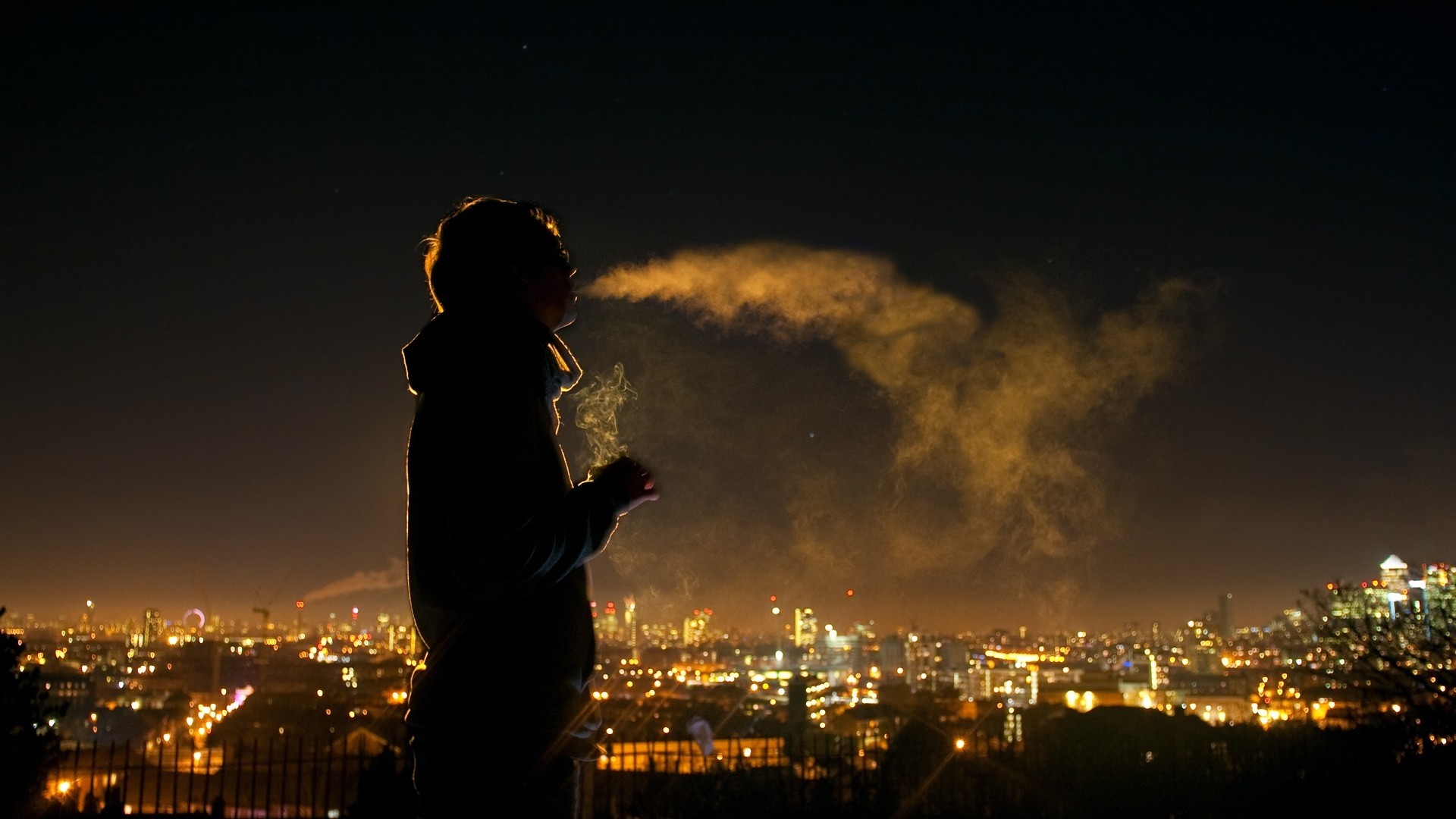 Person smoking in front of city lights at night HD Wallpaper