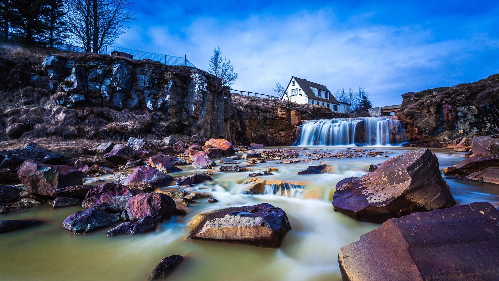 House and waterfall by river with rocks HD Wallpaper