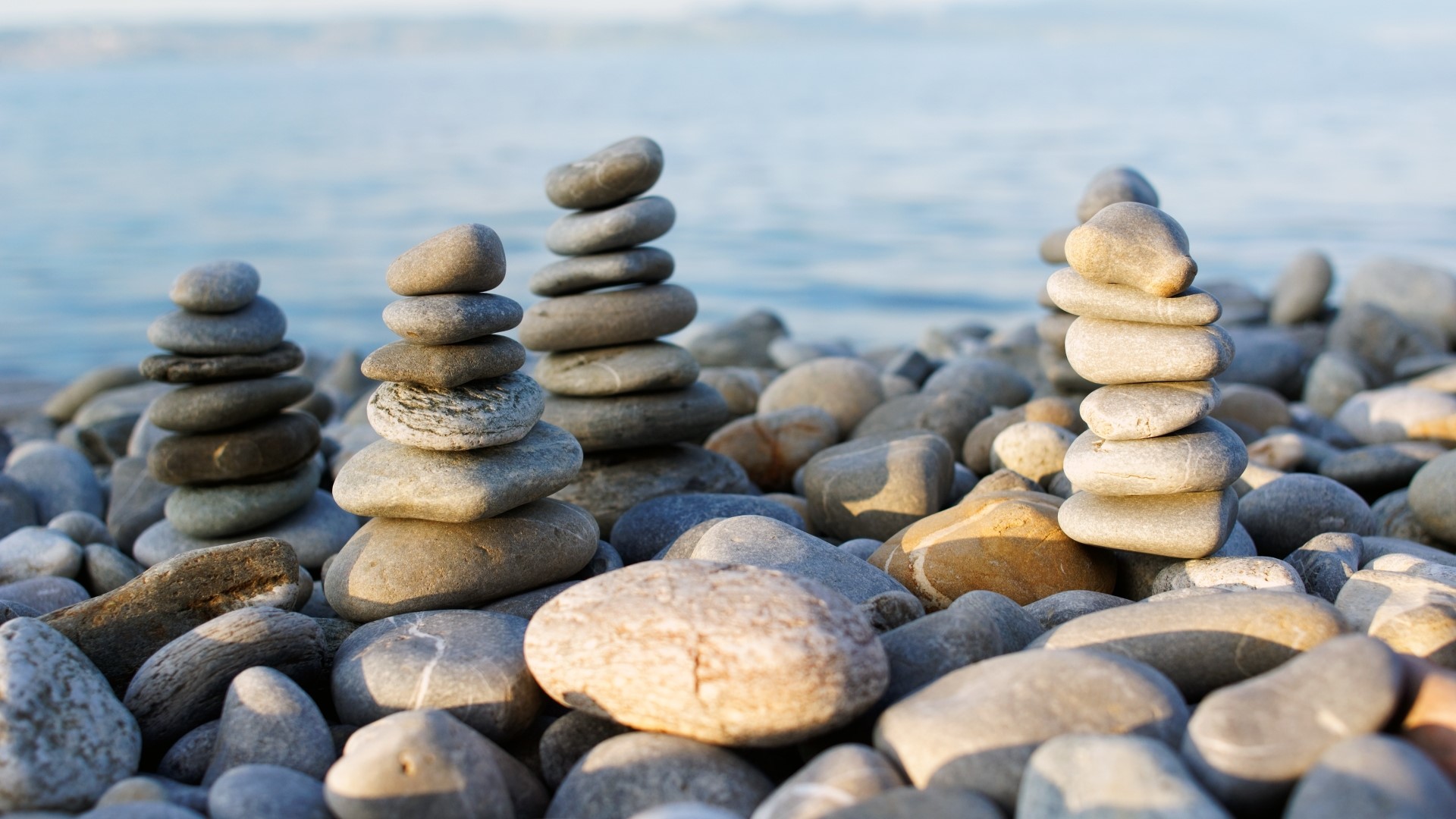 Stacked rocks on a beach with ocean in background HD Wallpaper