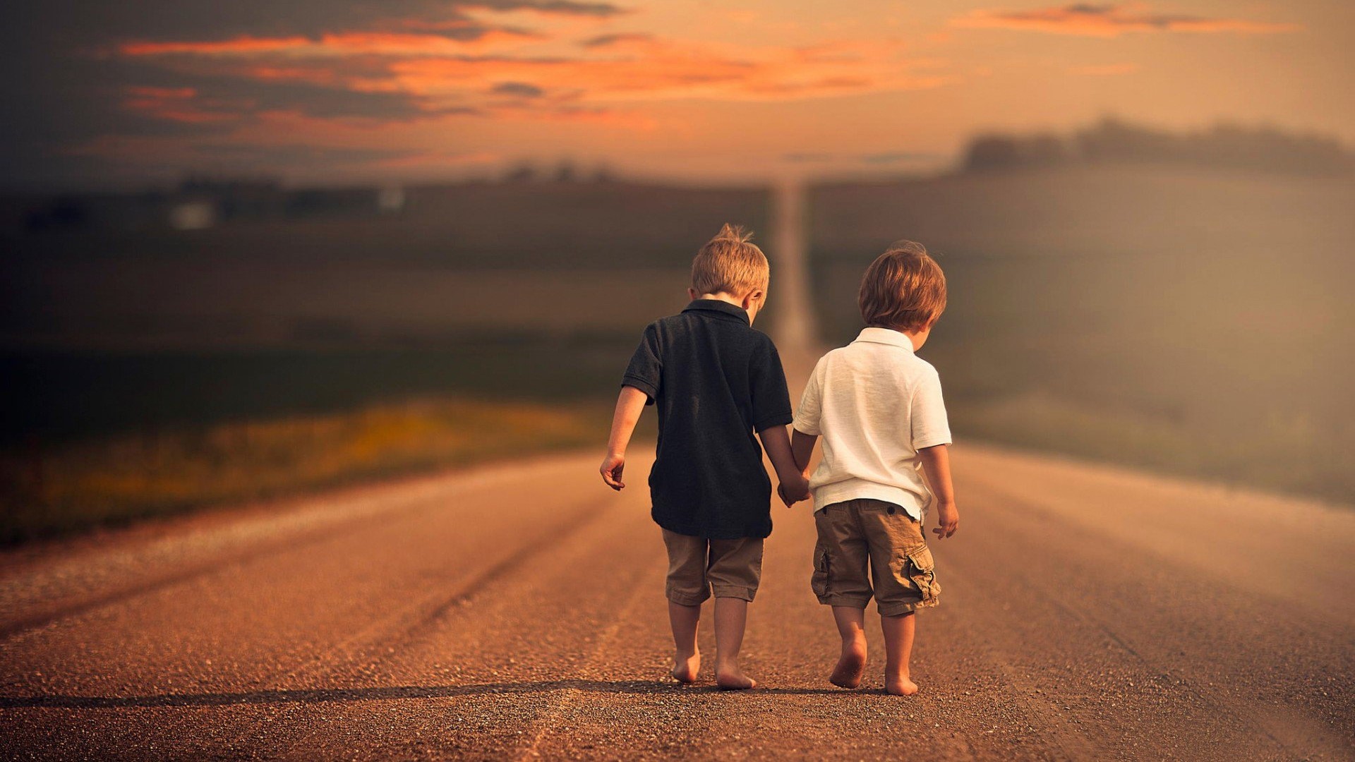 Two young boys holding hands walking down a dirt road HD Wallpaper