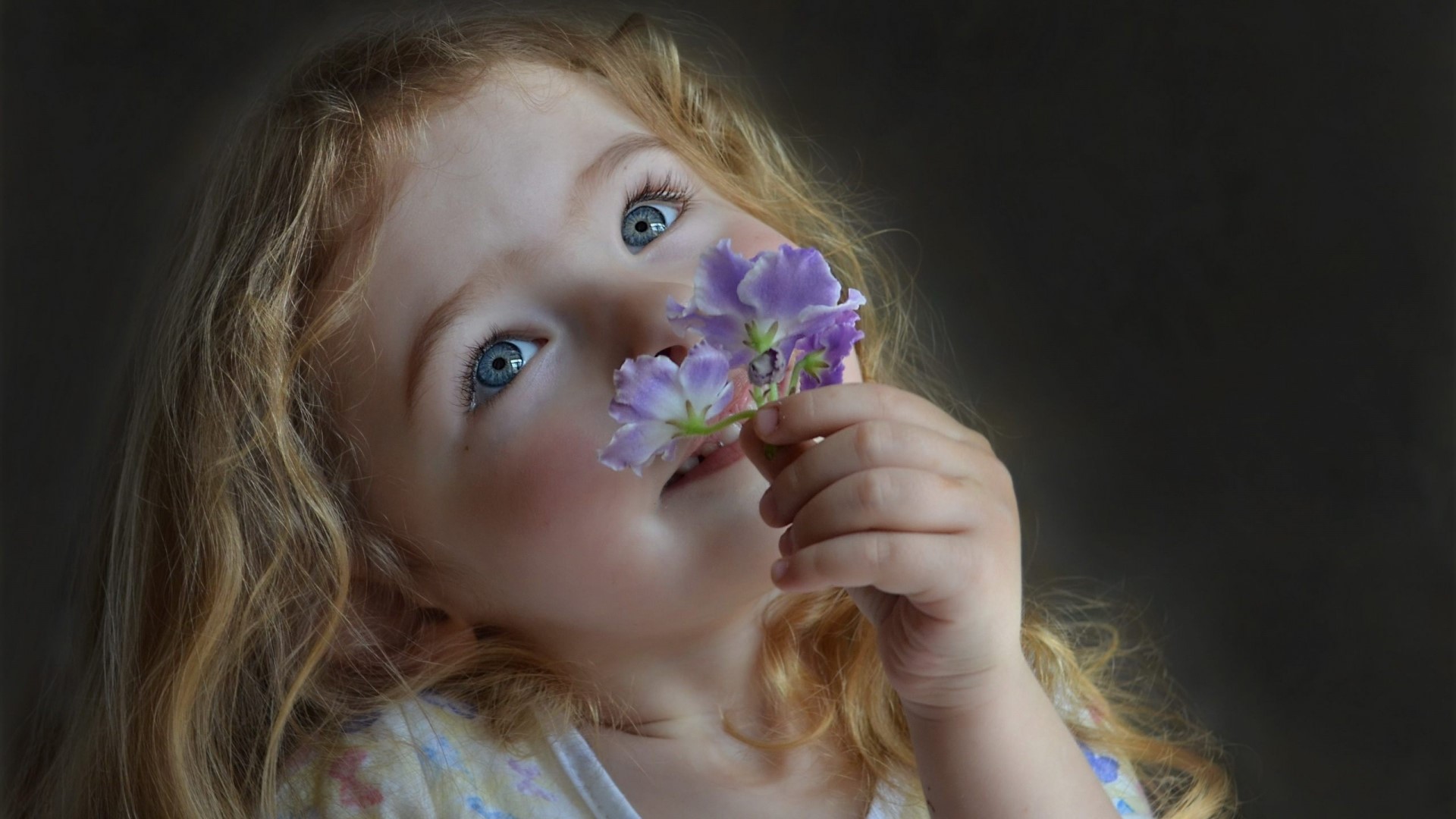 Little girl smelling purple flowers HD Wallpaper