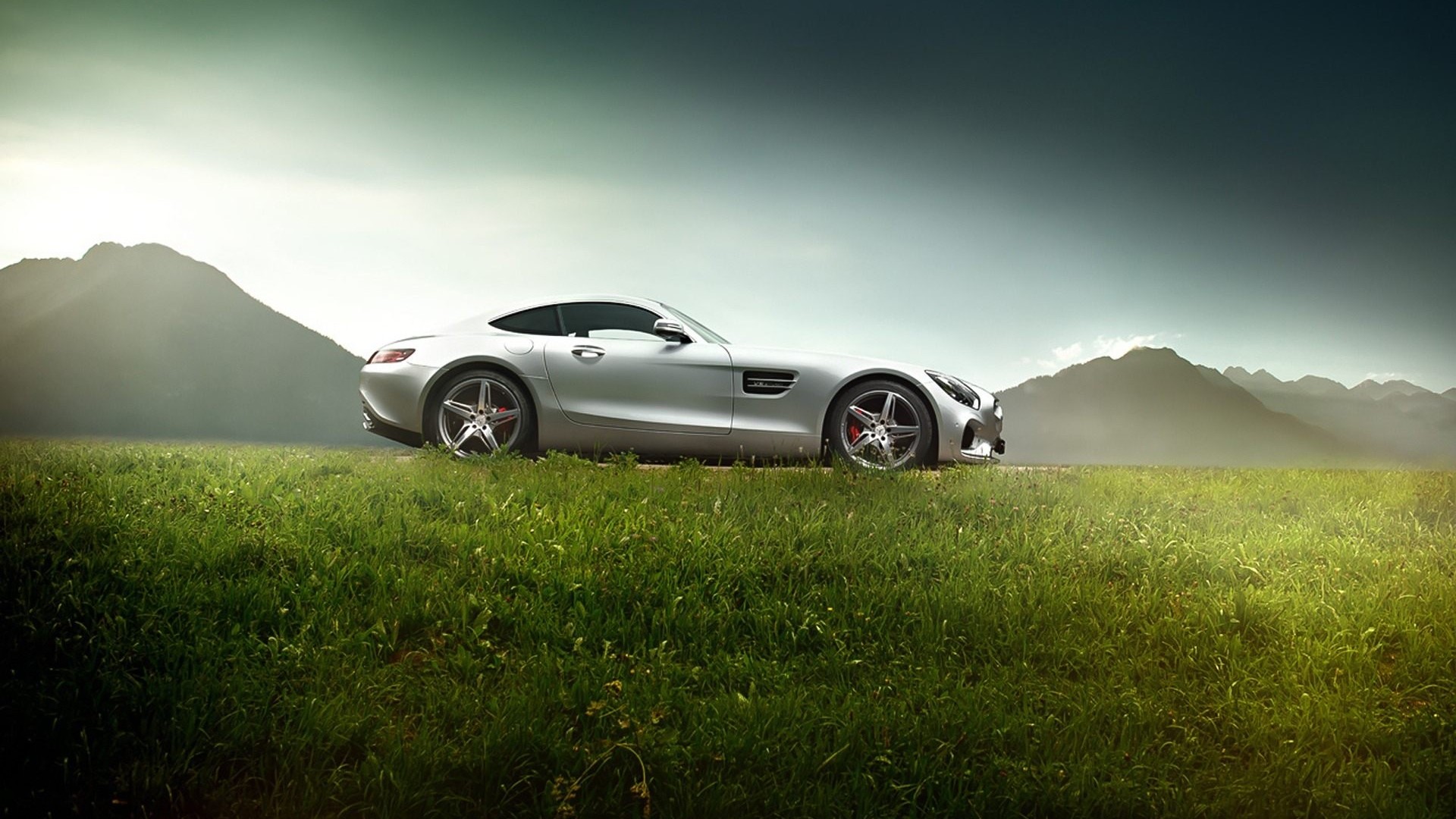 Silver Mercedes-Benz AMG GTS parked in a grassy field with mountains HD Wallpaper