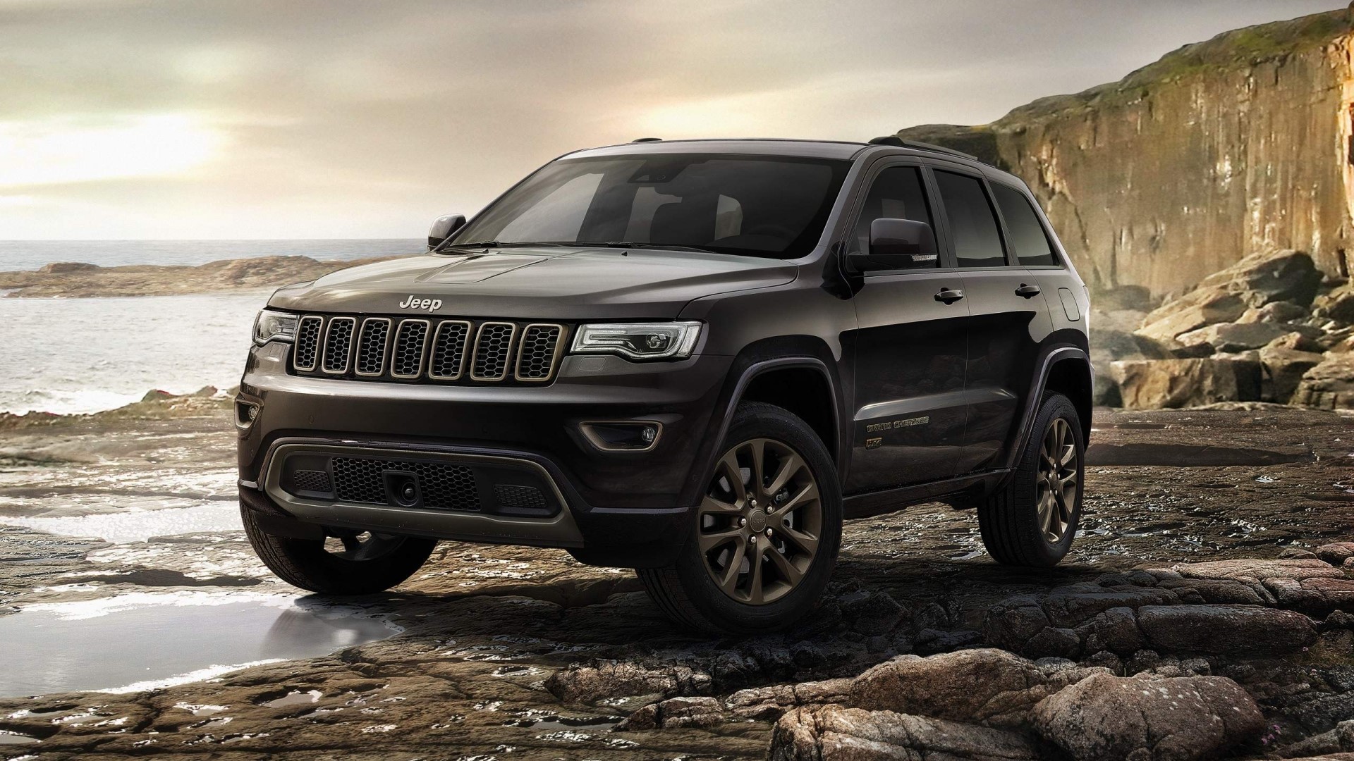 Jeep Grand Cherokee parked on rocky shore HD Wallpaper