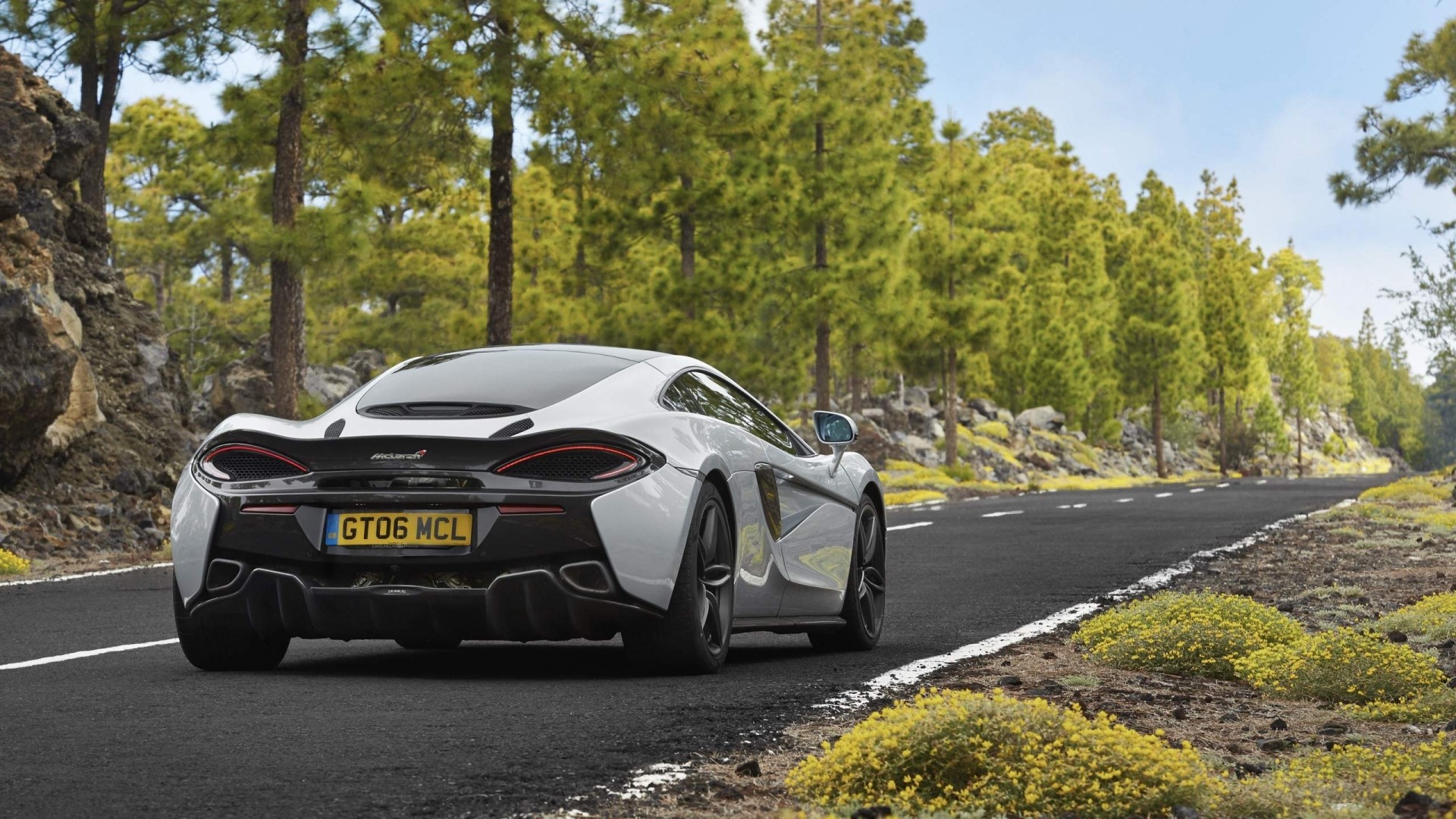 White McLaren GT on a road with trees HD Wallpaper